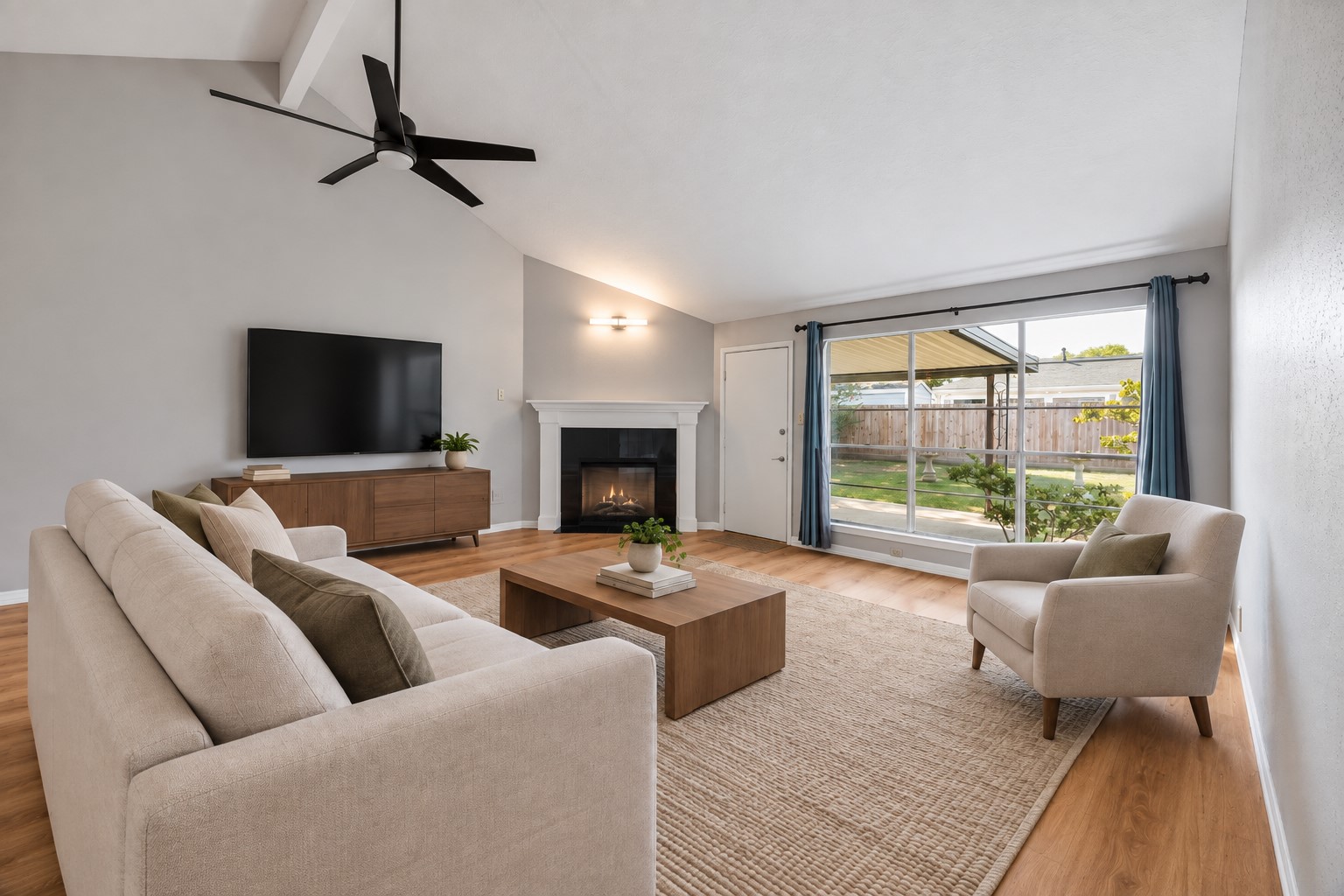 Expansive backyard-facing windows bring the outdoors into the living room, while the vaulted ceiling gives the seating area an open, airy feel.