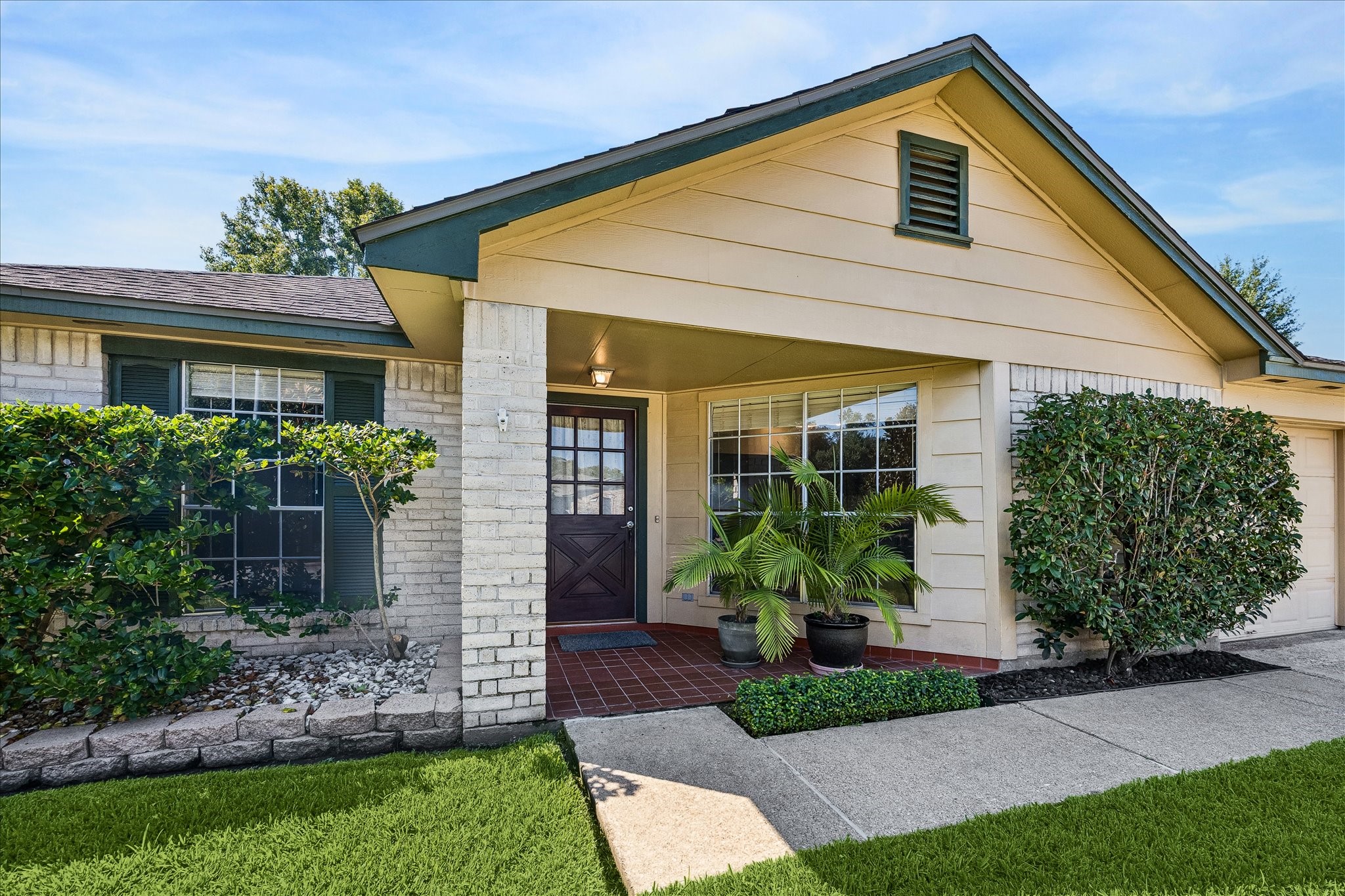 Covered front entry pairs brick and siding with established landscaping, creating a welcoming approach to the home.