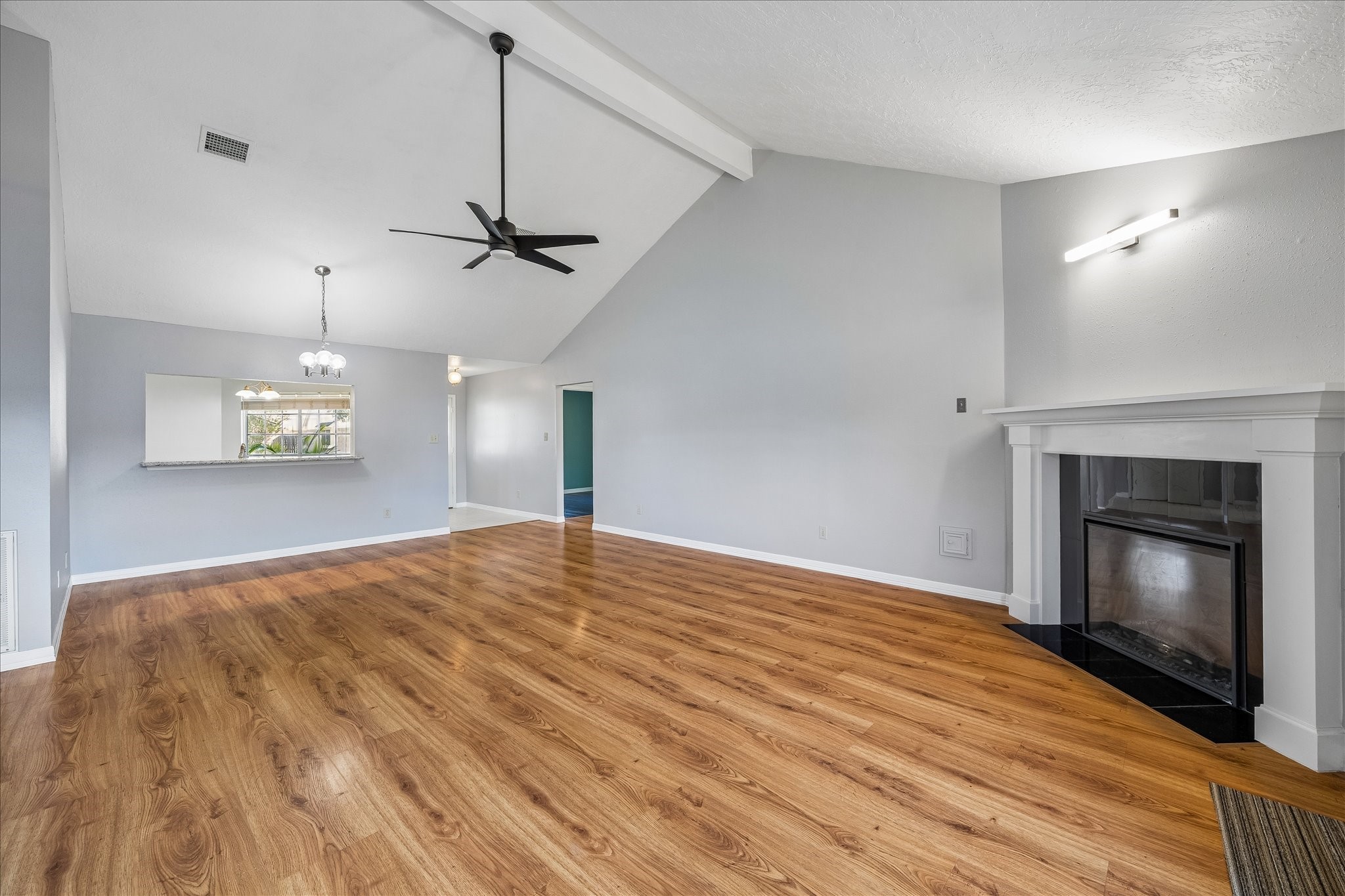 Vaulted ceilings and exposed beam detail bring extra volume to the living room, anchored by a remote-controlled electric fireplace and LED accent light installed in 2023.