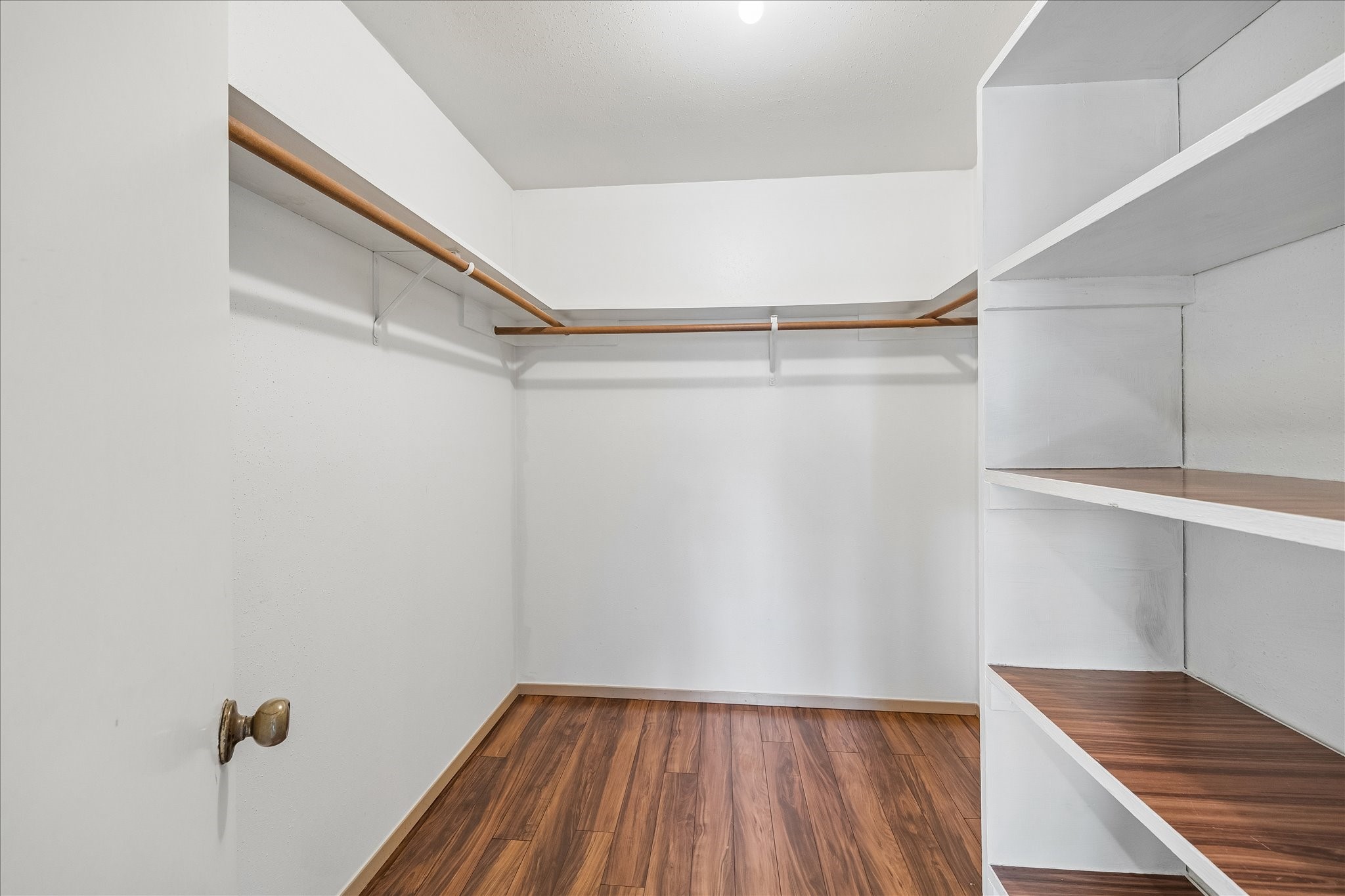 Walk-in primary closet is lined with wraparound hanging space and built-in shelving, keeping clothing and accessories neatly organized.