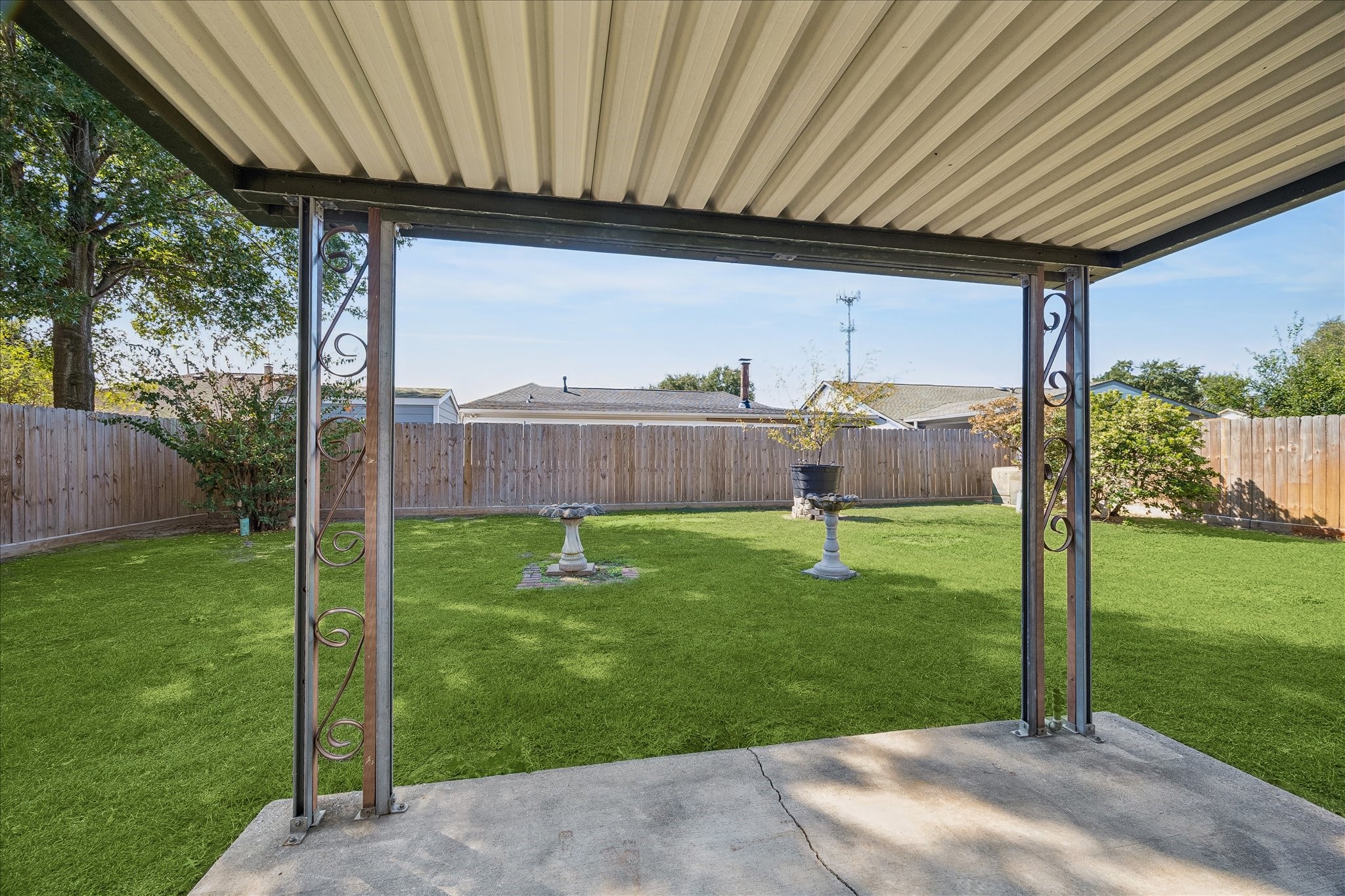 Covered back patio creates a shaded outdoor spot for grilling, dining, or relaxing while looking out across the fenced yard.