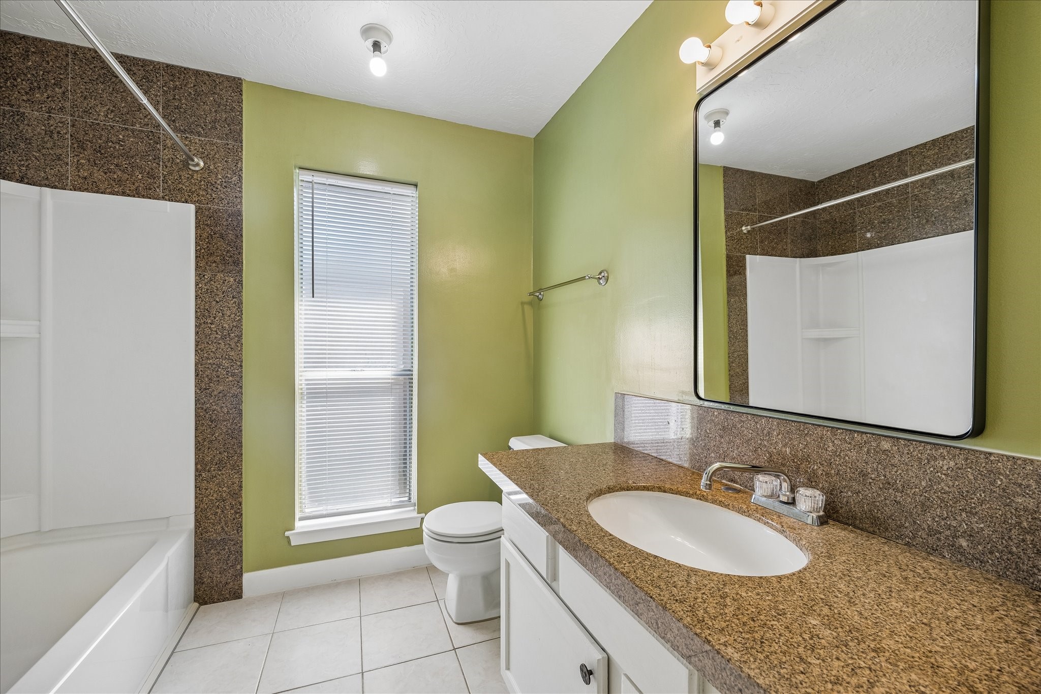 Guest bath features a tub and shower combination, broad vanity, and tall window for additional light.