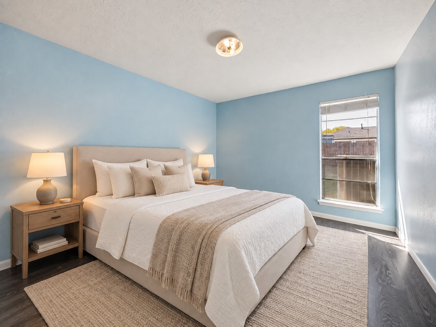 Second guest bedroom offers a comfortable footprint with soft blue walls and a tall window bringing in plenty of daylight.