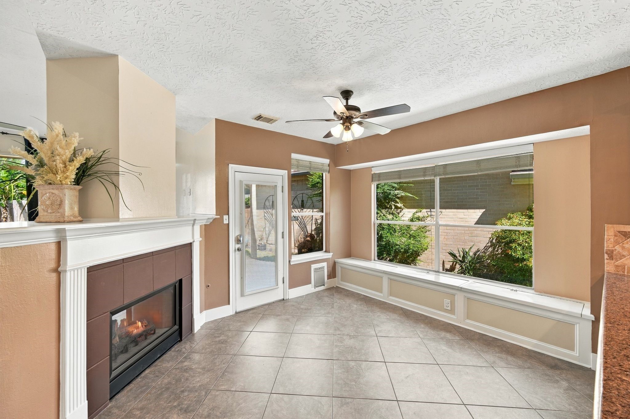 Experience the inviting charm of this bright and airy living space, featuring a cozy fireplace, elegant tile flooring, and abundant natural light streaming through large windows, perfect for creating your dream home.