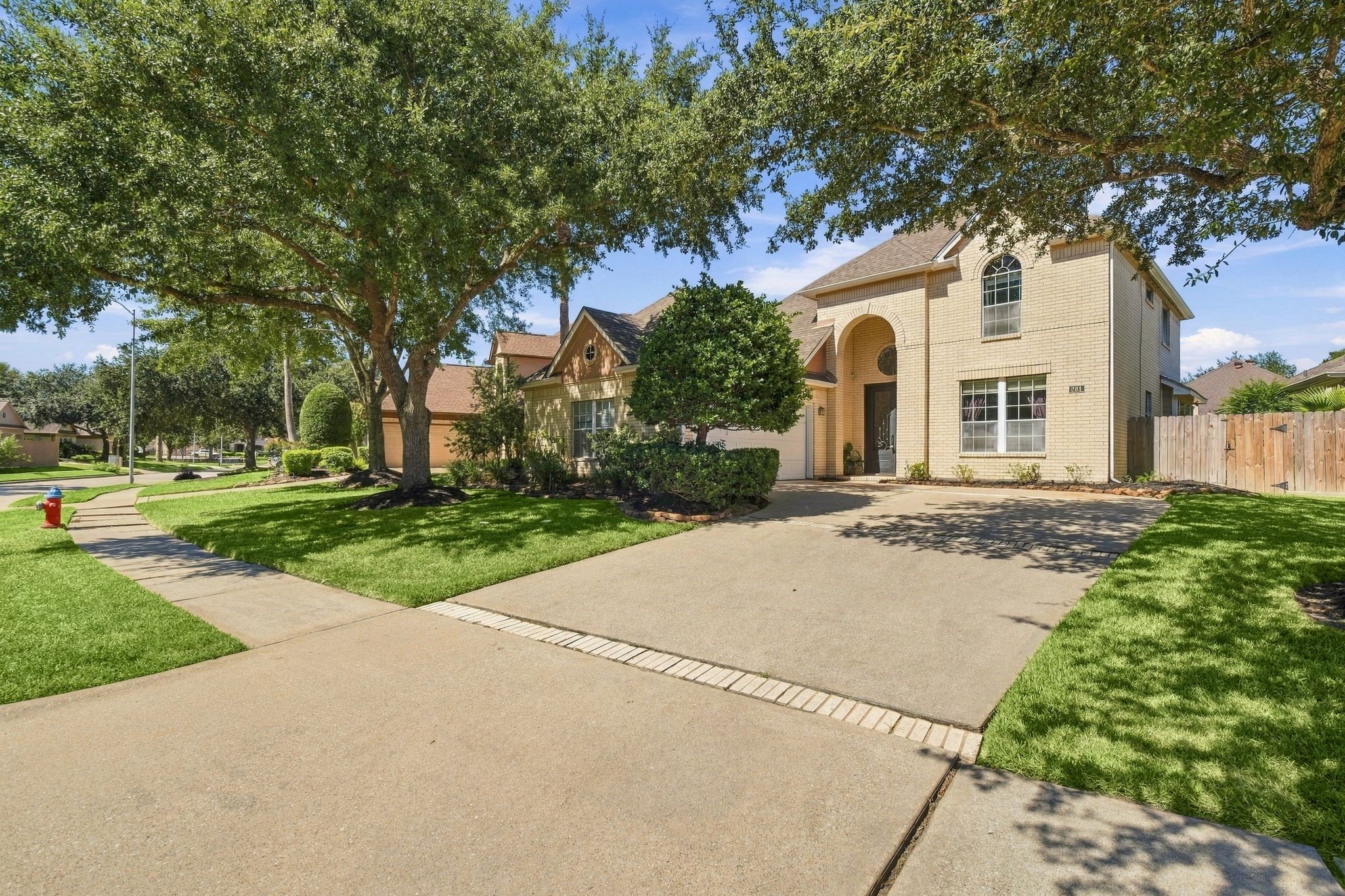 Charming home with a spacious driveway leading to a convenient two-car garage, nestled amid lush greenery.