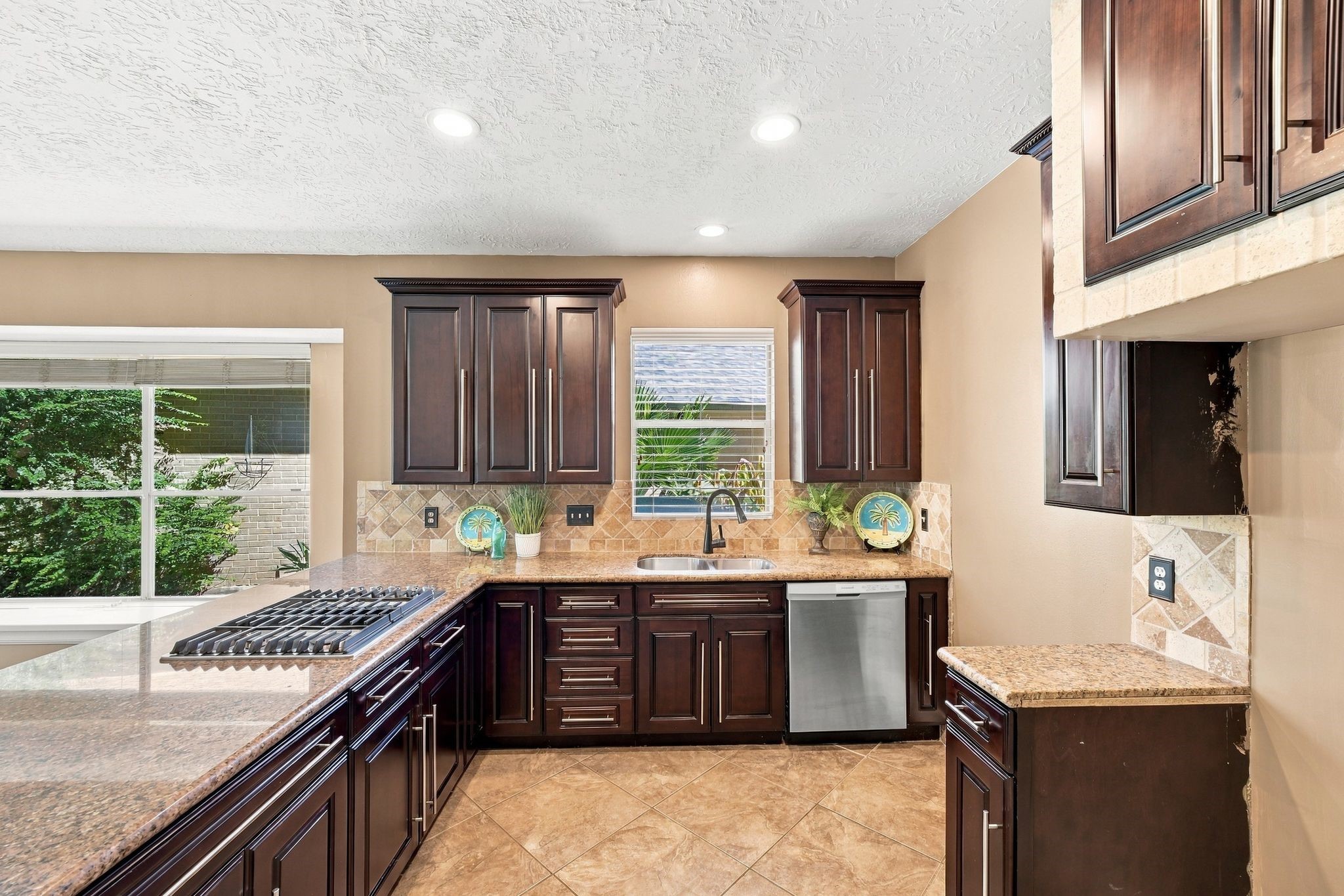 Discover a kitchen where elegance meets functionality, featuring rich dark wood cabinetry, sleek countertops, and abundant natural light for a warm, inviting atmosphere.