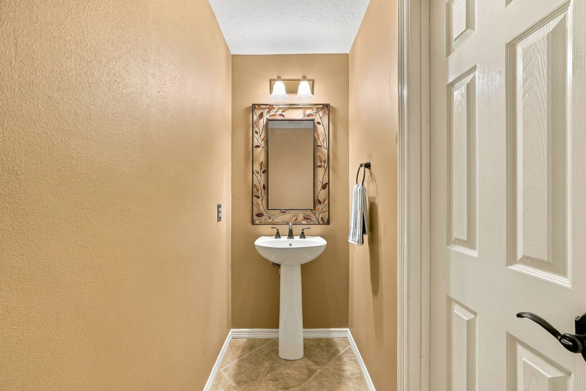 Conveniently located on the first floor, this charming half bath features warm tones and elegant fixtures, offering both style and functionality for guests.