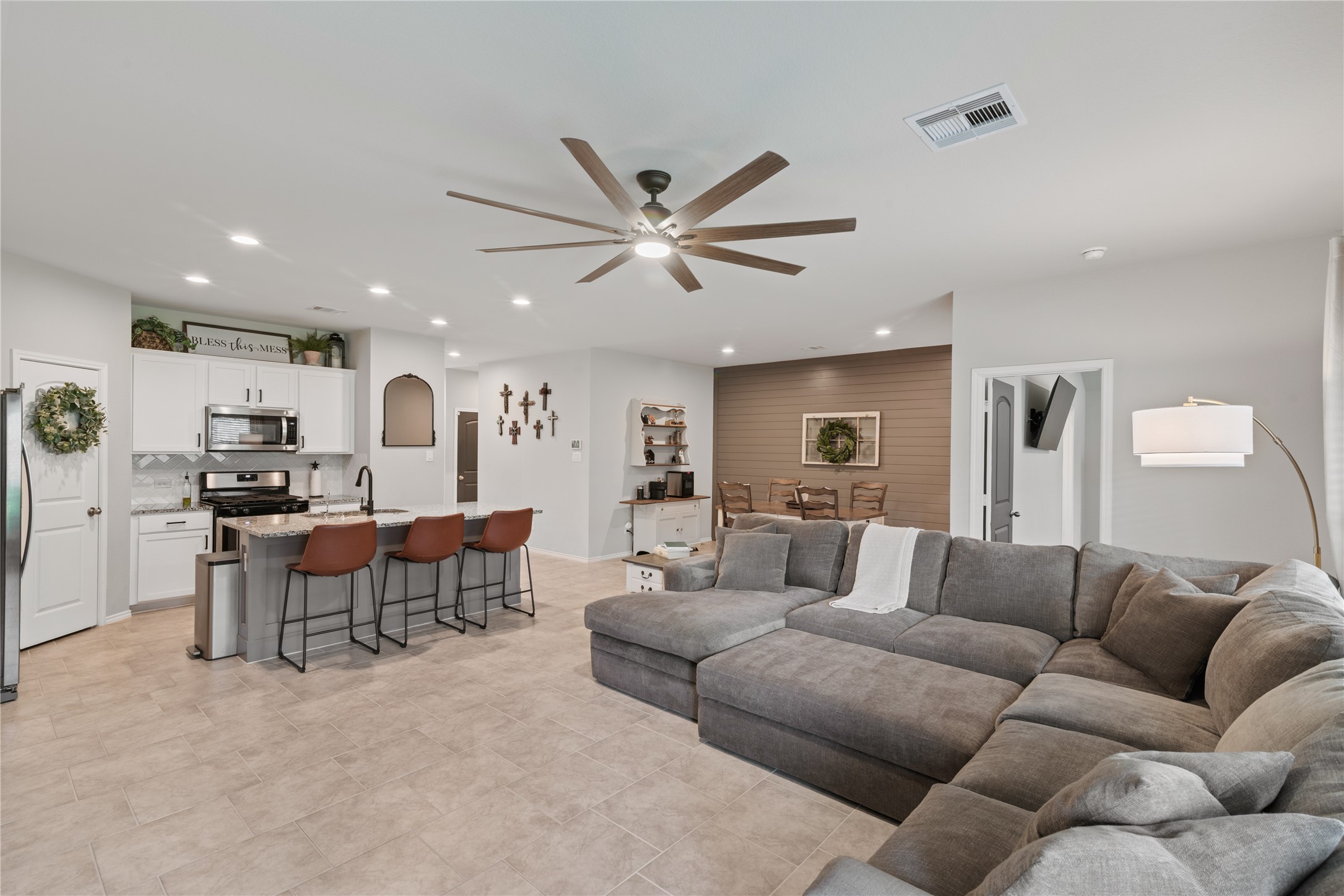 Spacious open-concept living area with a modern kitchen featuring stainless steel appliances and a large island with seating. Cozy sectional sofa and stylish dining space complete the inviting ambiance.