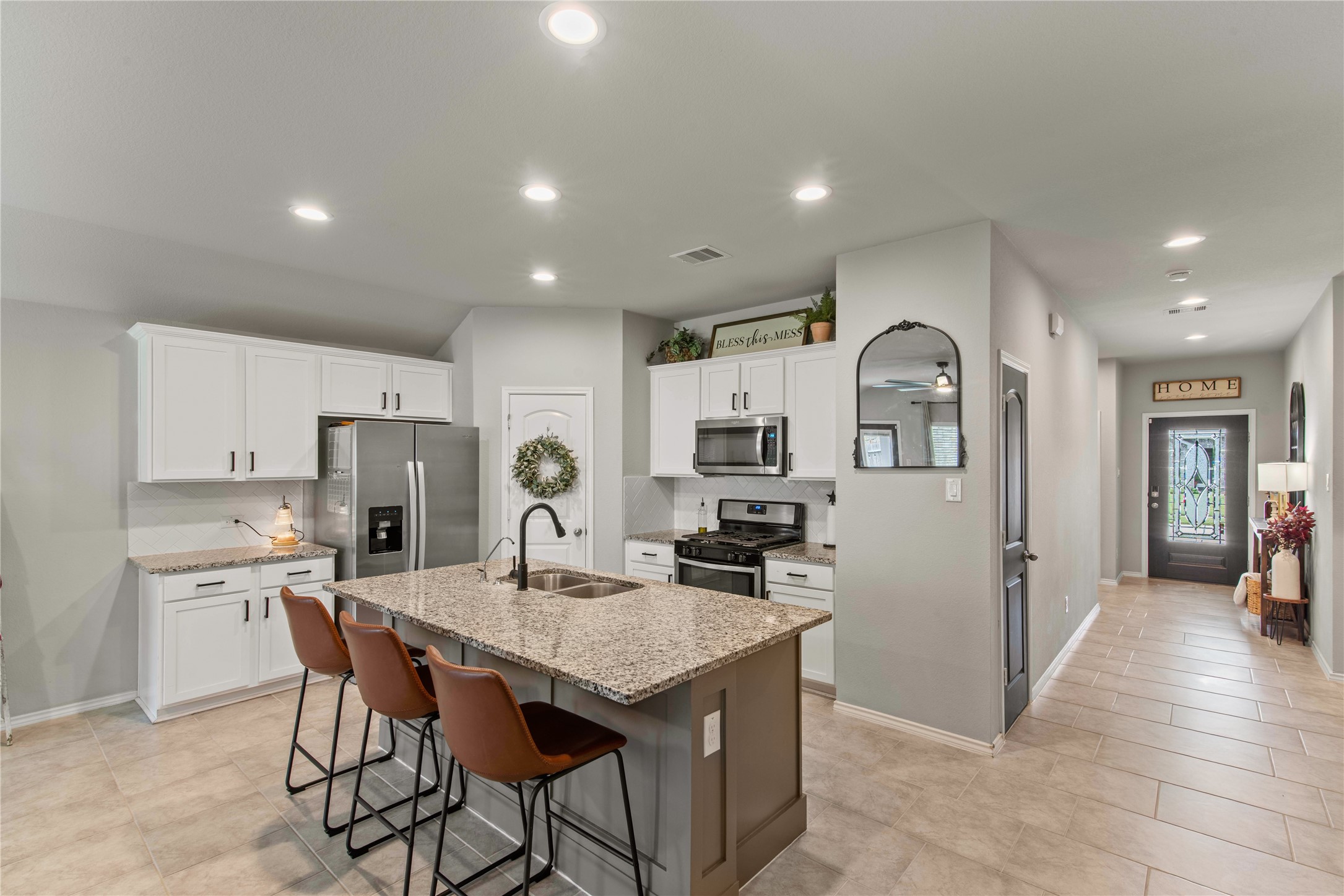 Modern kitchen with granite countertops, stainless steel appliances, and a central island with seating. Bright and welcoming entryway with stylish decor and ample lighting.