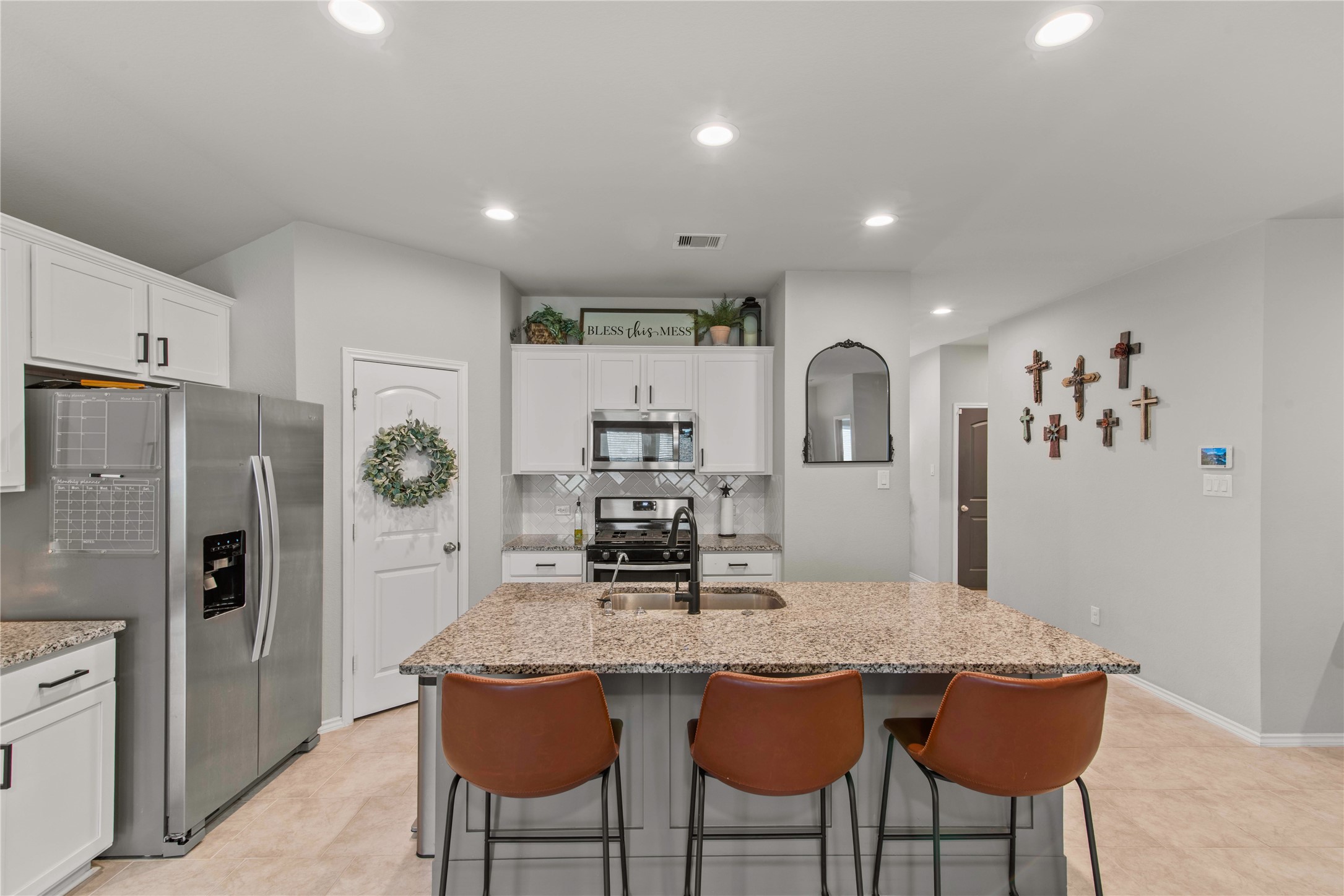Modern kitchen with granite countertops, stainless steel appliances, and a central island with seating. Bright and inviting space with stylish decor and ample storage.