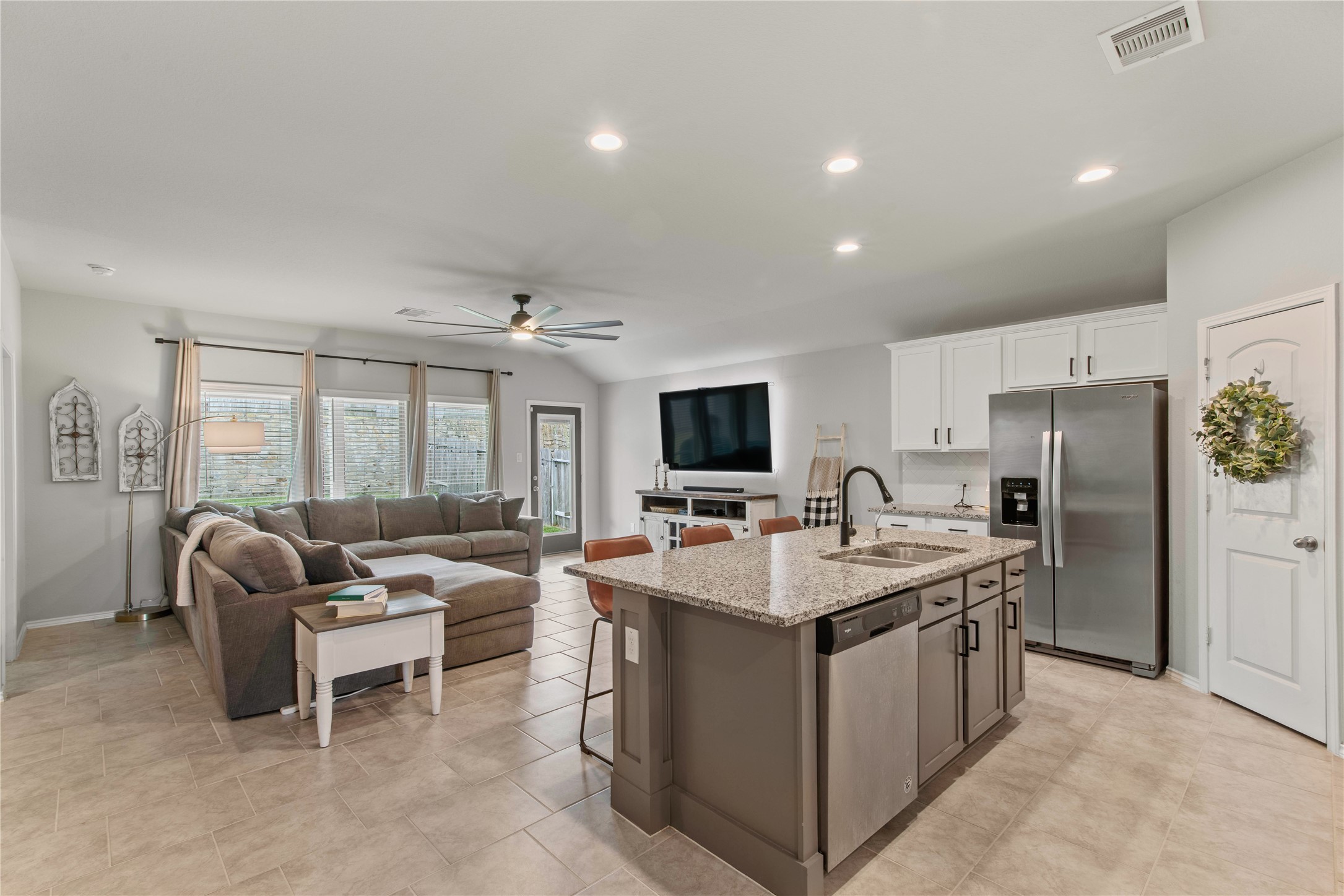 Spacious open-concept living area with a modern kitchen featuring granite countertops, stainless steel appliances, and a cozy living room with abundant natural light.