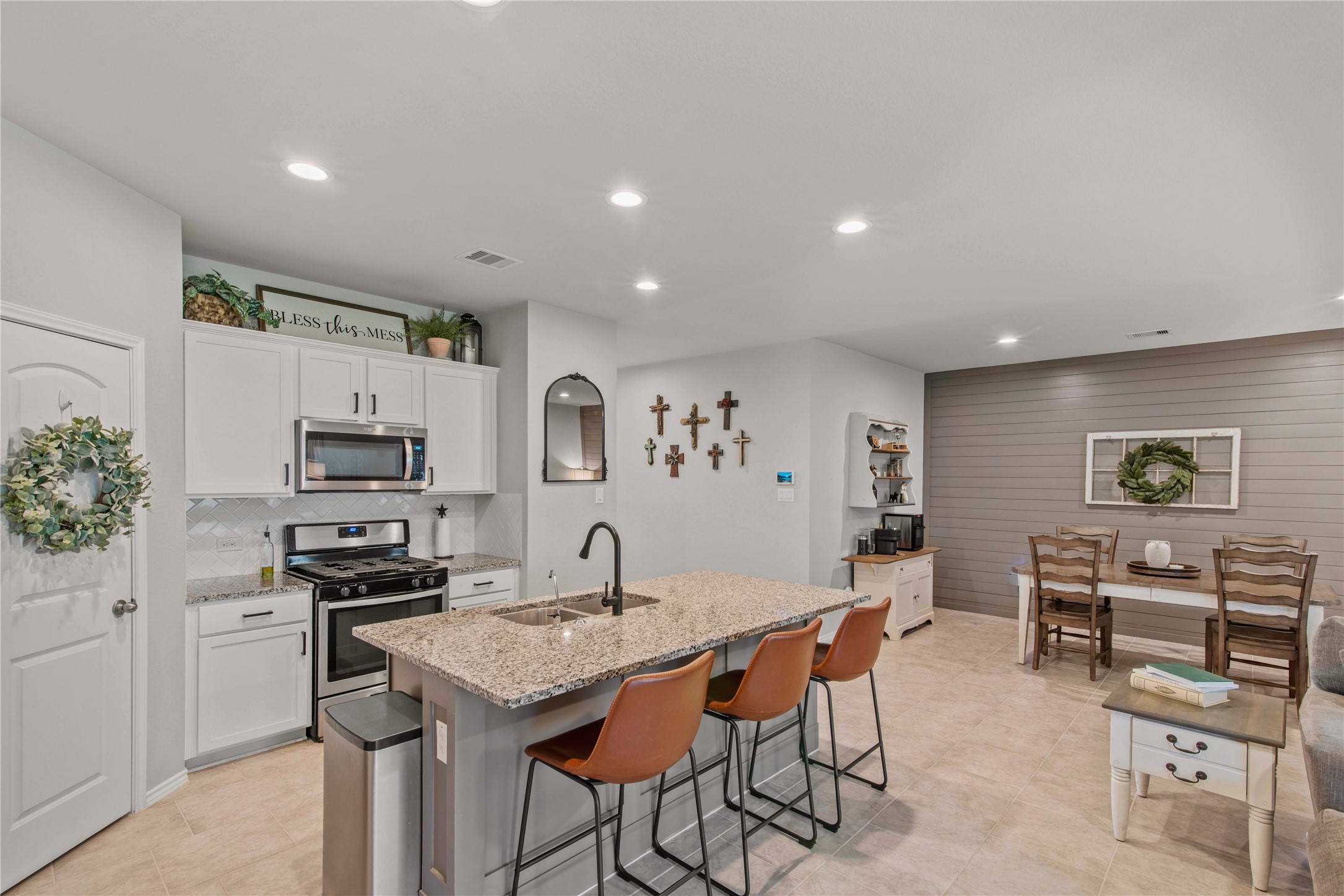 Spacious kitchen with modern appliances, a large granite island with seating, and an adjacent dining area featuring stylish shiplap walls.