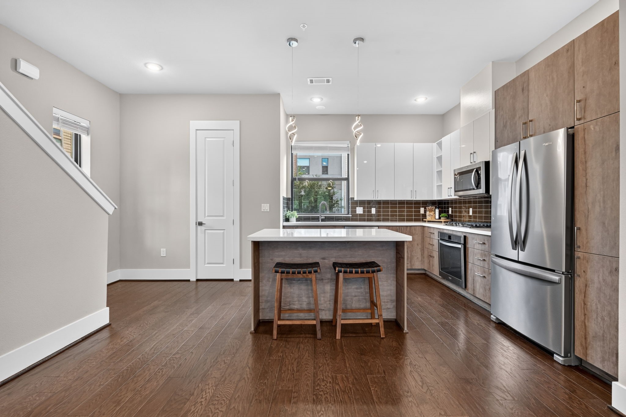Here is a closer view of the kitchen with updated pendant lighting, modern cabinetry and all SS appliances included. The 2nd floor also has a powder bath which is the doorway in the back left corner.