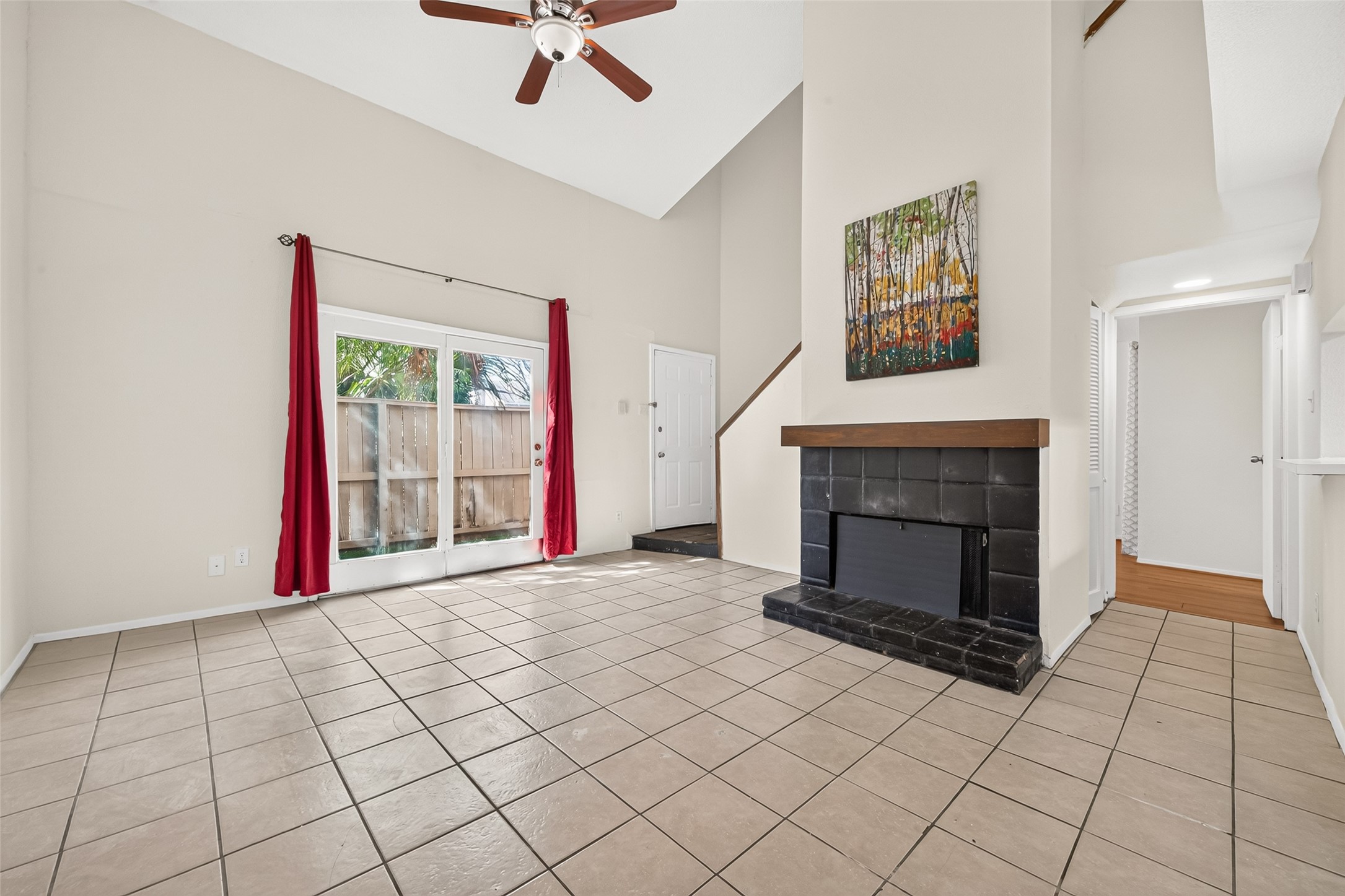 Spacious living area with high ceilings, featuring a cozy fireplace.