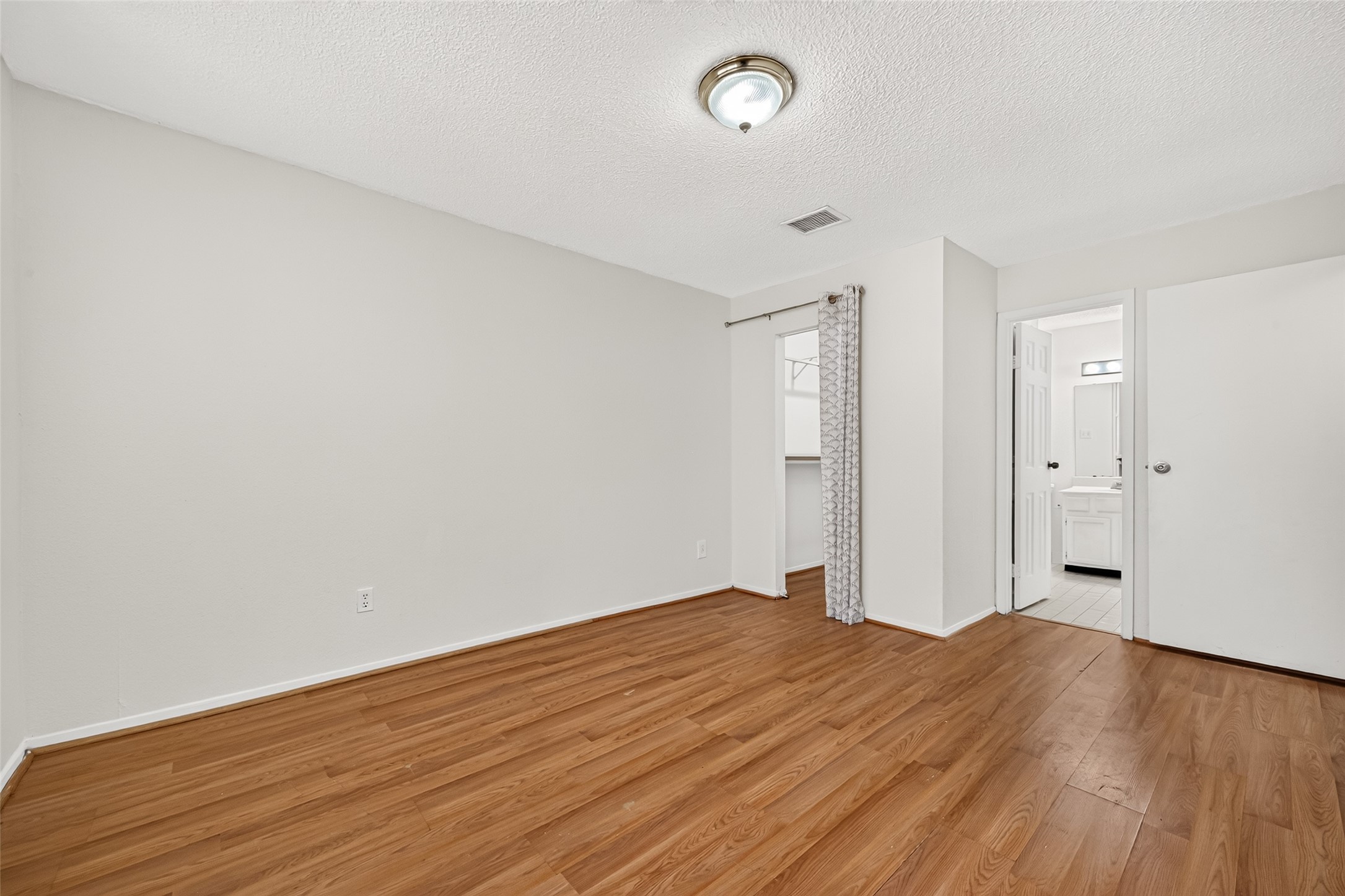 Anotherview of primary bedroom with a walk-in closet and full bath.