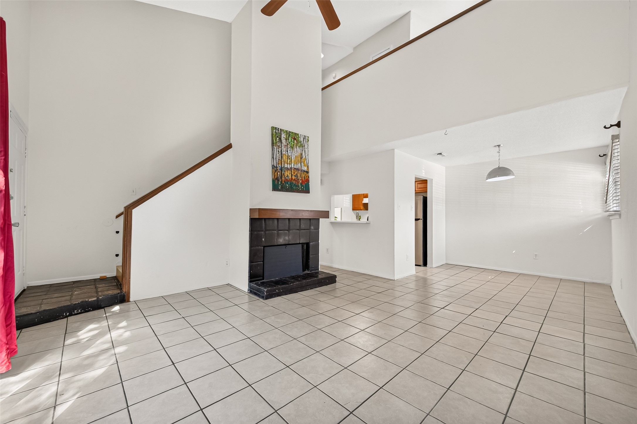 Welcome to this living room with high ceilings, tile flooring, & a ceiling fan.
