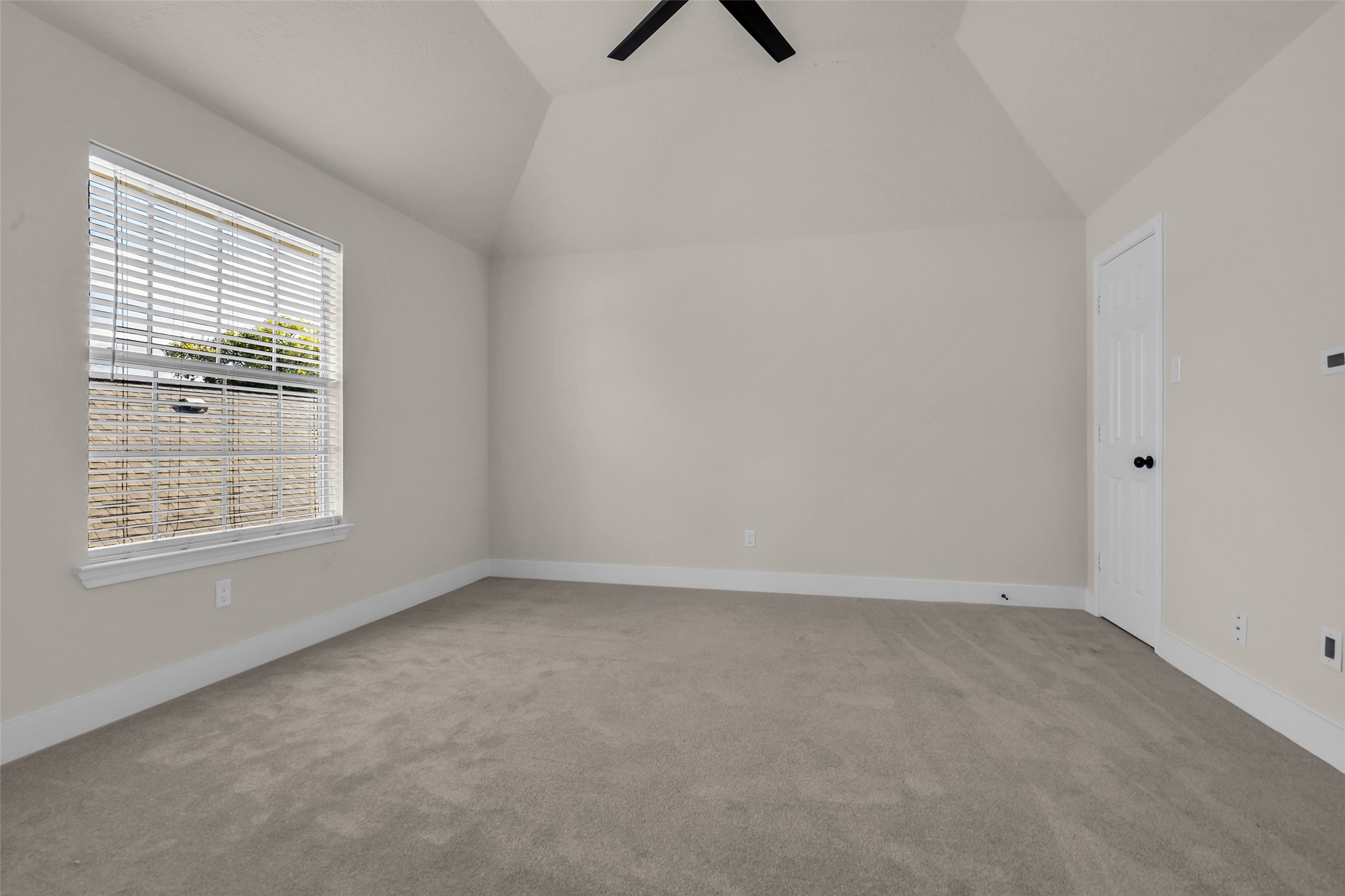 Next bedroom with high ceilings, neutral walls, and soft carpet, featuring a large window that allows natural light to fill the space.