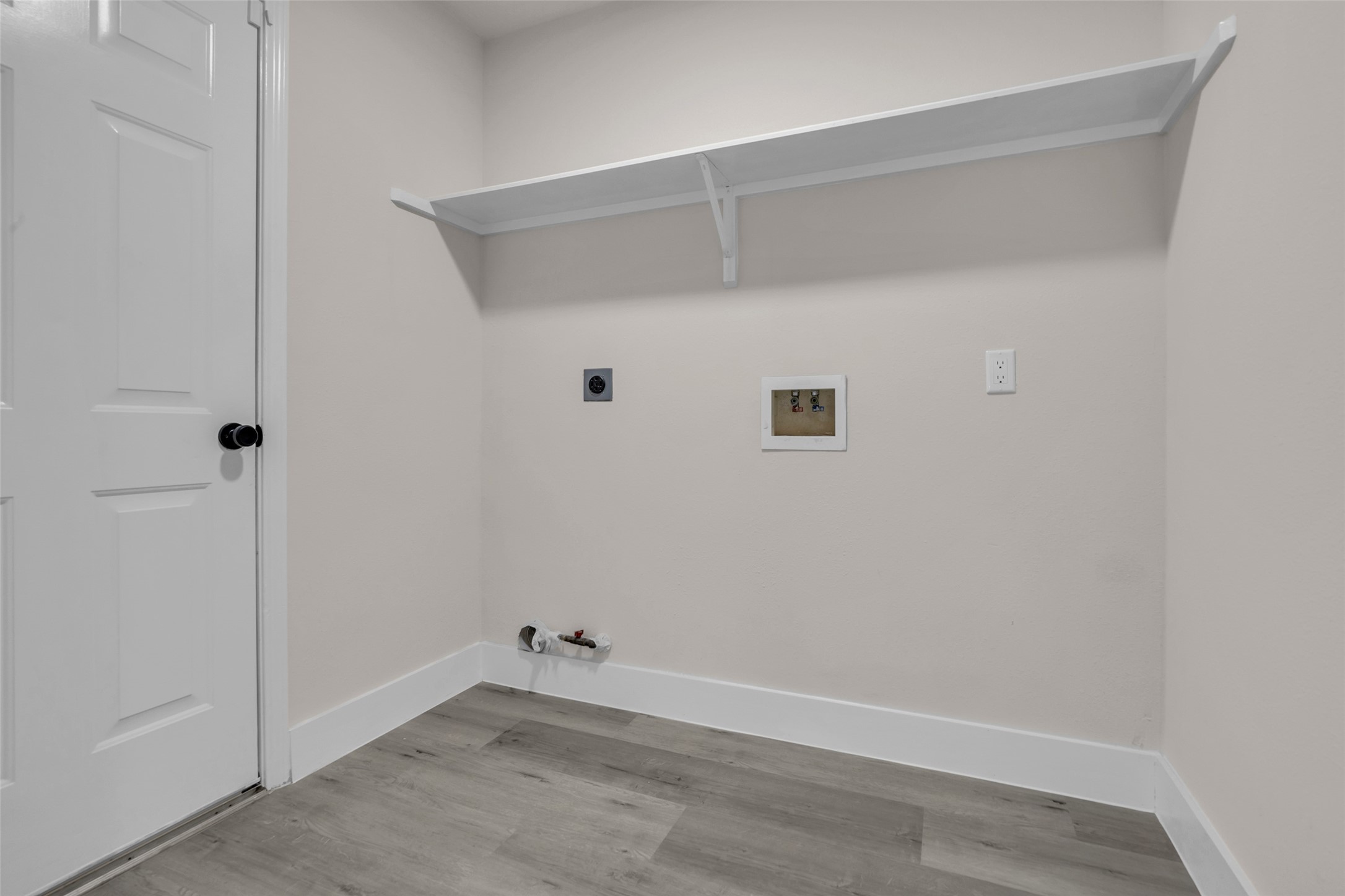 Convenient laundry area with hookups for washer and dryer, featuring a built-in shelf for additional storage.