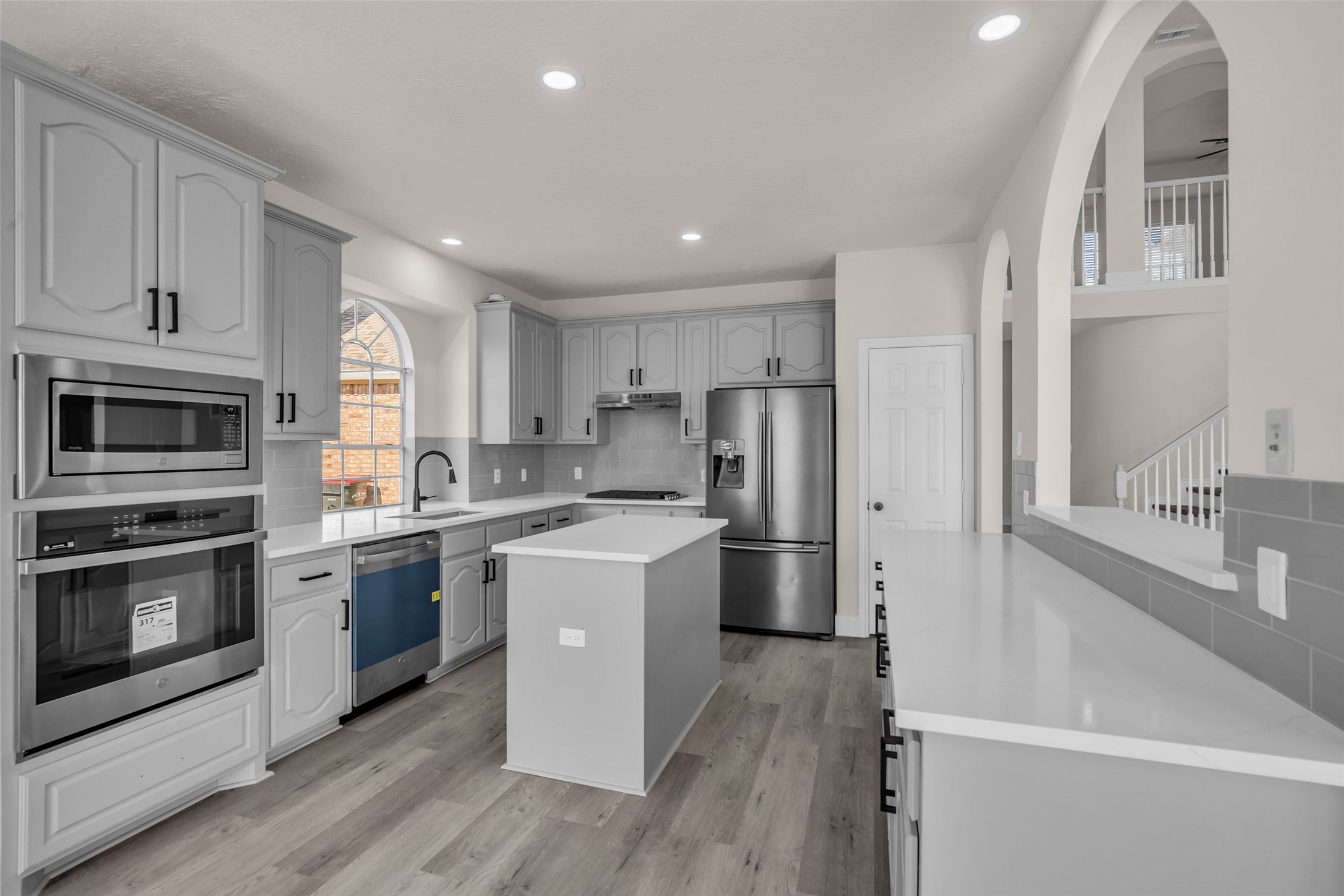 A modern kitchen with sleek stainless steel appliances, elegant gray cabinetry, and a central island, perfect for culinary enthusiasts. The space is enhanced by a kitchen window for all that natural light!