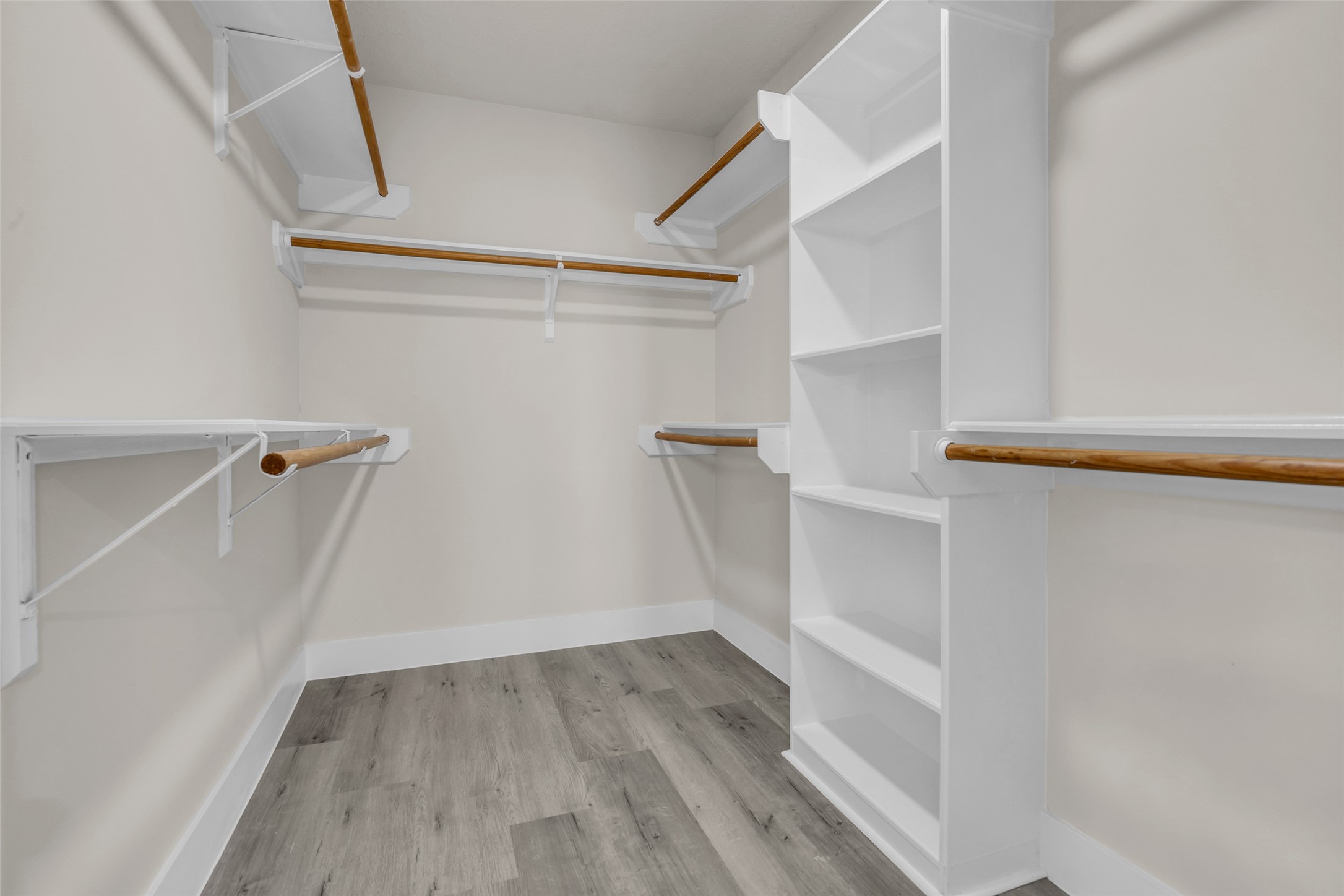 Spacious walk-in closet featuring multiple hanging rods and built-in shelving for optimal organization.