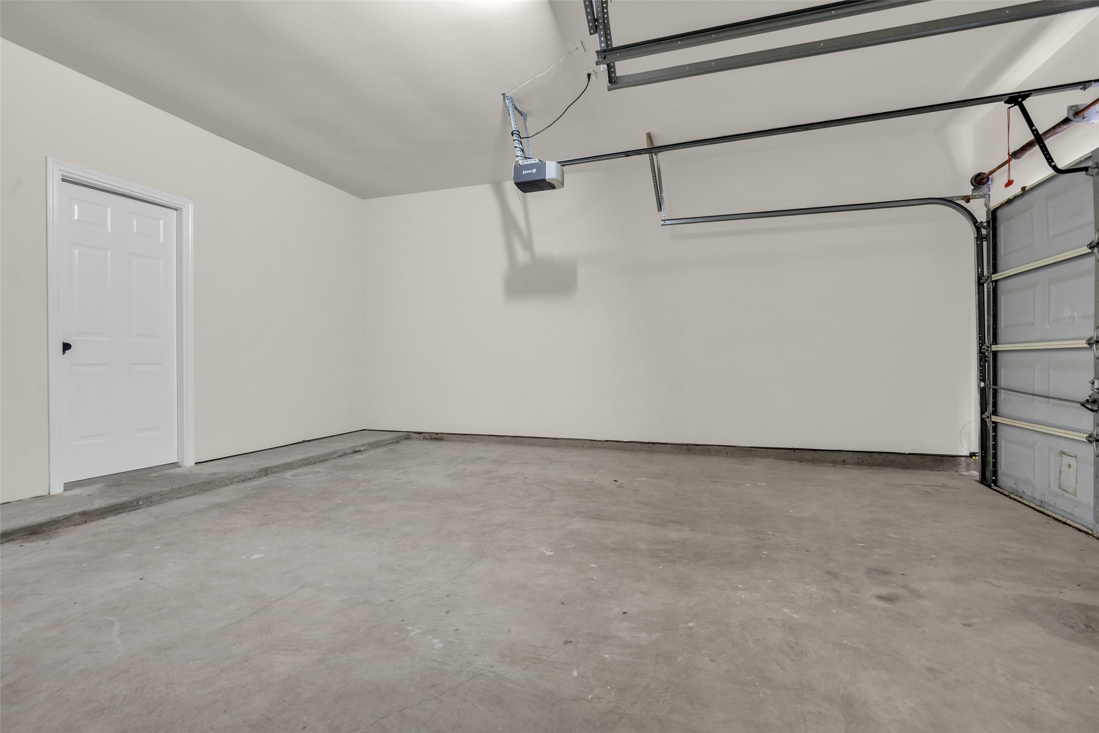Spacious and clean garage with ample room for storage and parking, featuring a modern automatic door opener for convenience.
