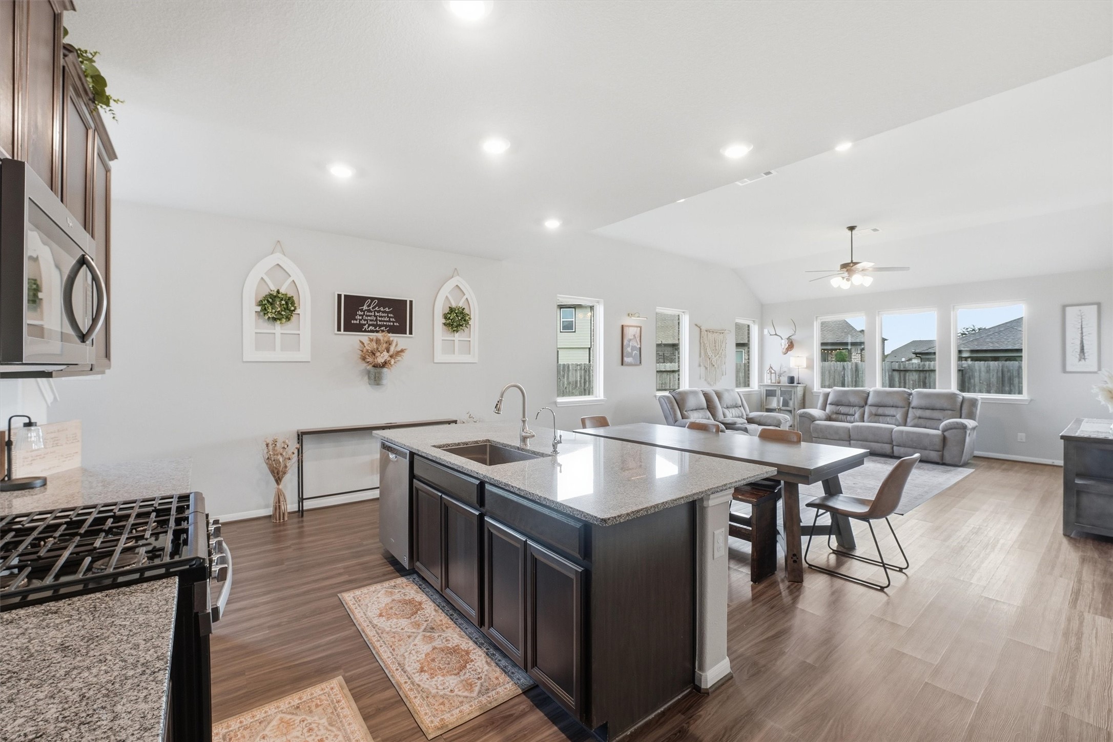 Open-concept kitchen and living area. The kitchen features modern appliances, a large island with seating, and dark cabinetry. The space transitions smoothly into a cozy living room with ample natural light from multiple windows. Open-concept kitchen and living area. The kitchen features modern appliances, a large island with seating, and dark cabinetry. The space transitions smoothly into a cozy living room with ample natural light from multiple windows.