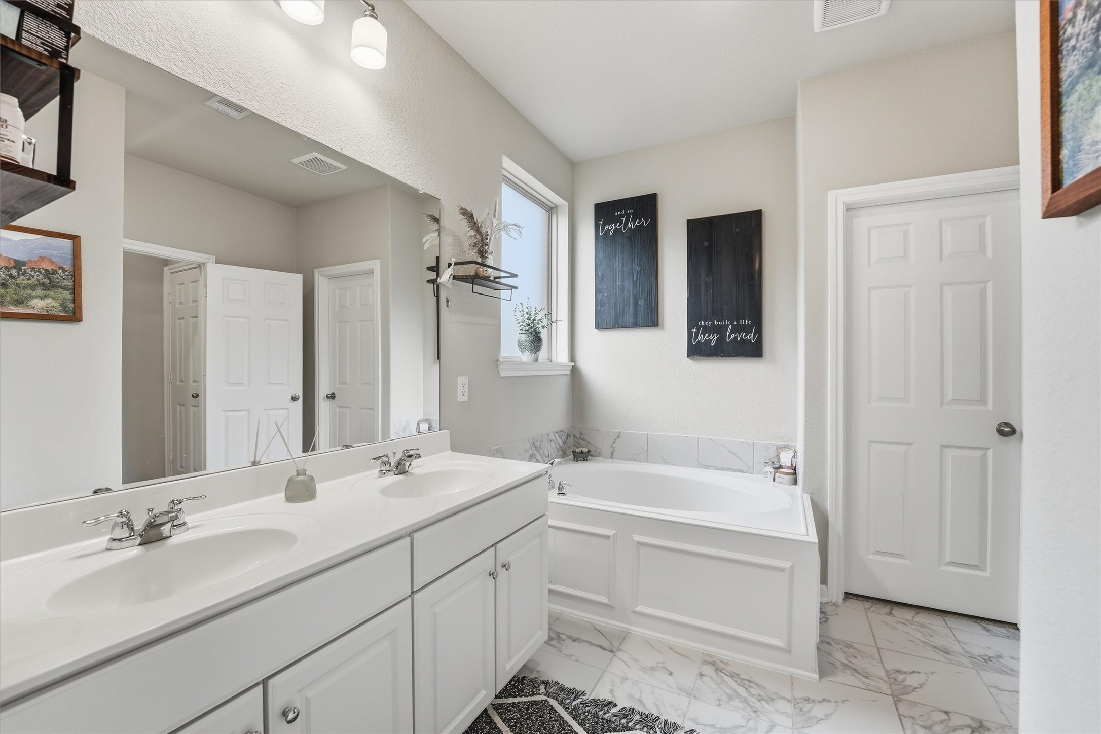 Primary bathroom features a double vanity with sleek sinks, a spacious garden tub and large closet.