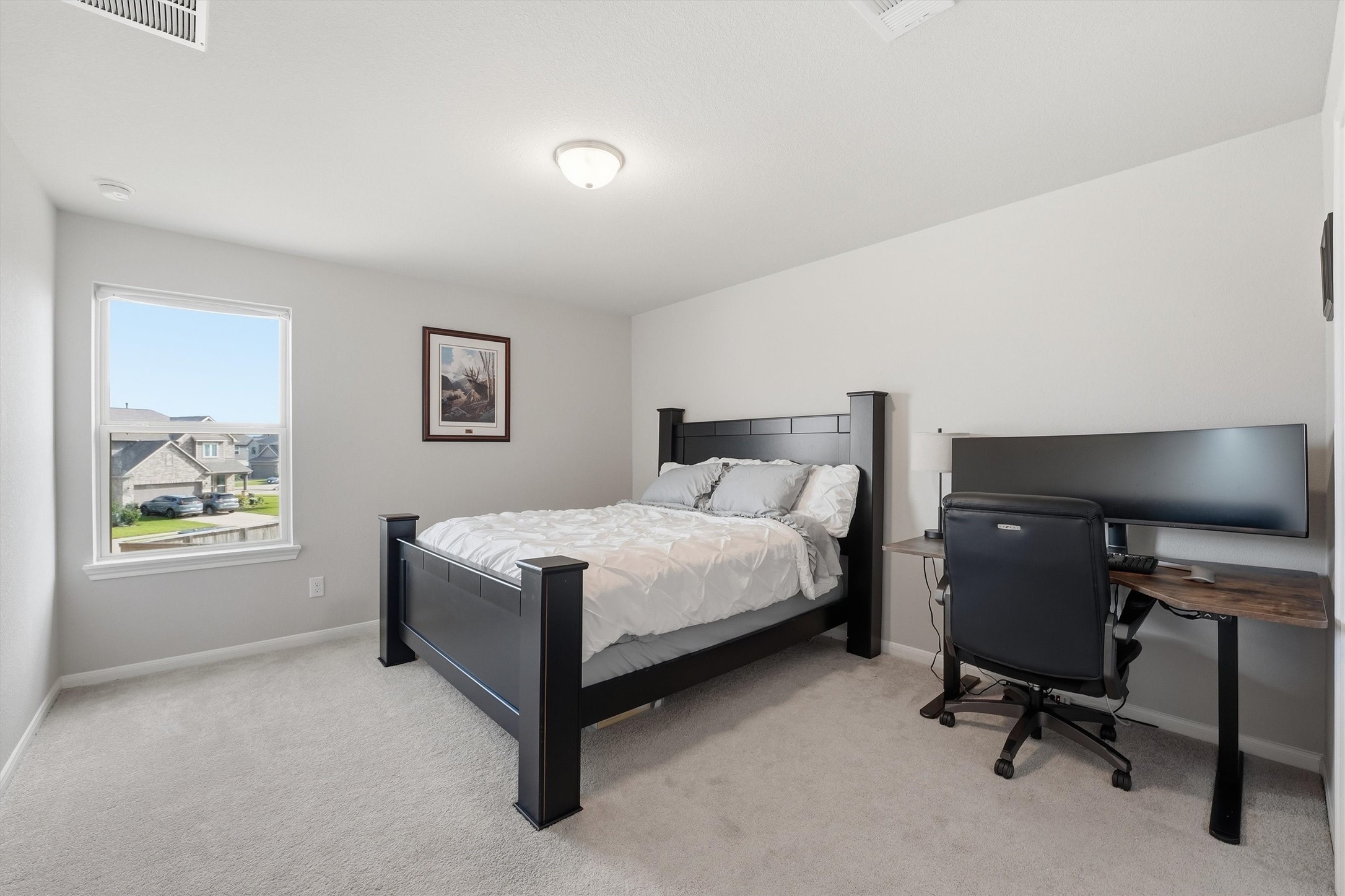 A bright bedroom with a large window offers natural light, large closet and a neighborhood view.