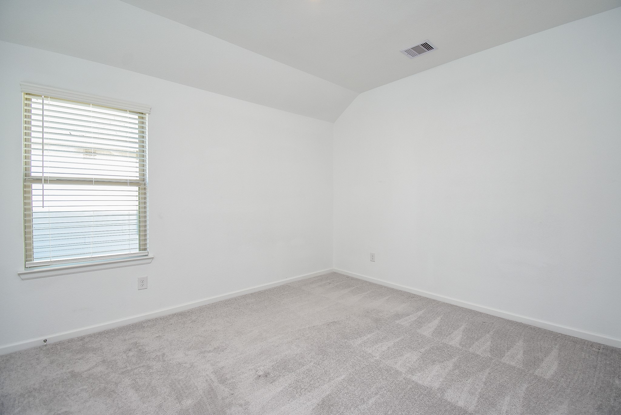 One of the two secondary bedrooms with neutral carpeting and large window.