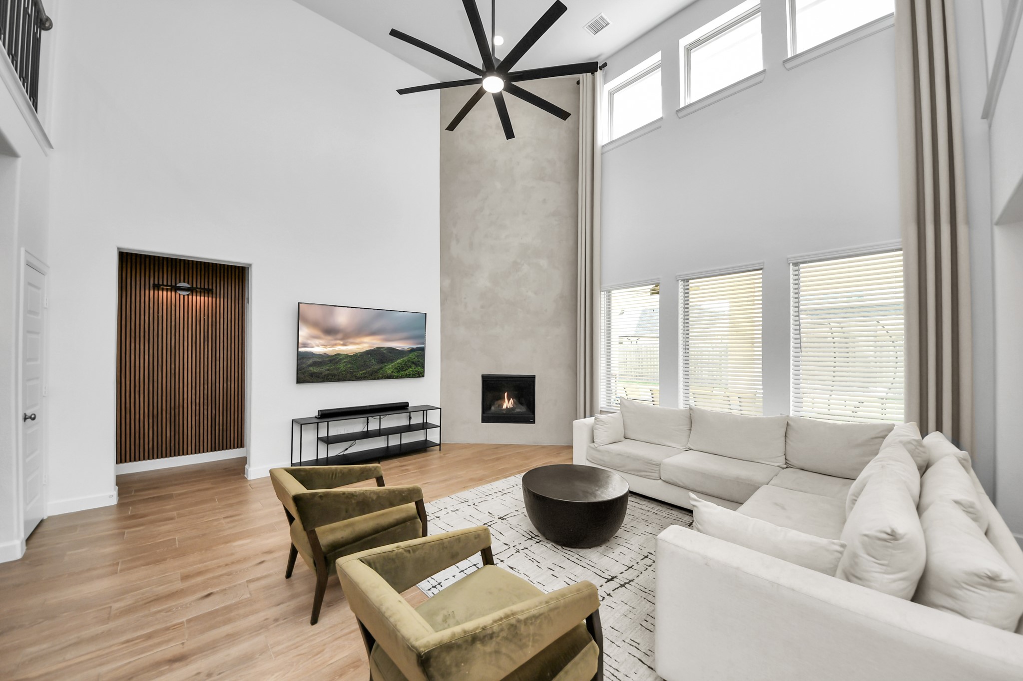Spacious and modern living room with high ceilings, a sleek fireplace, and large windows for abundant natural light.