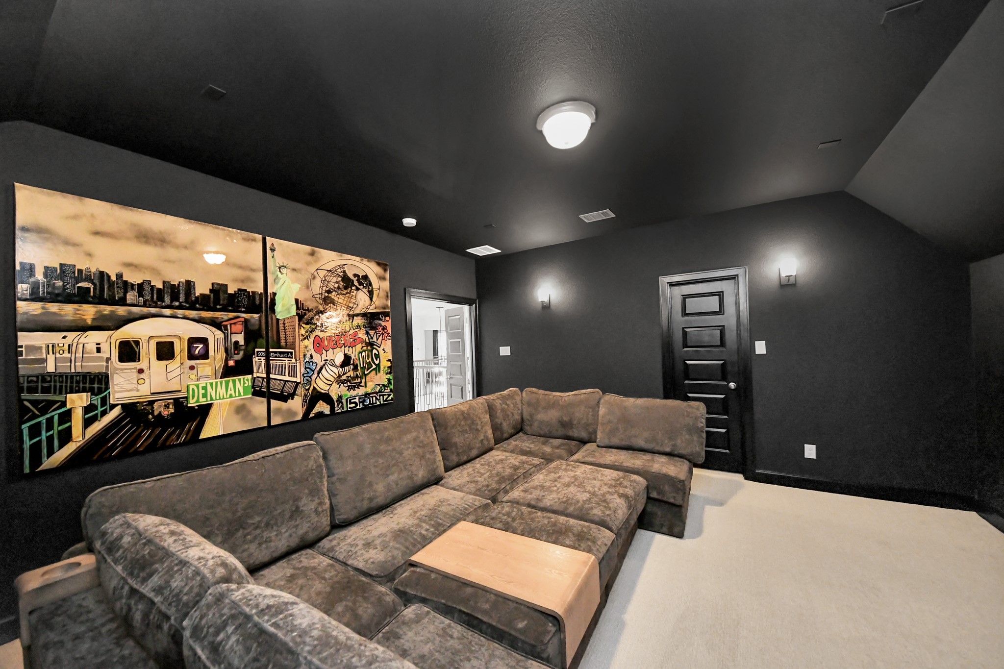Experience ultimate relaxation in this stylish media room, featuring a plush L-shaped sectional, modern lighting, and vibrant wall art for a cozy entertainment haven.