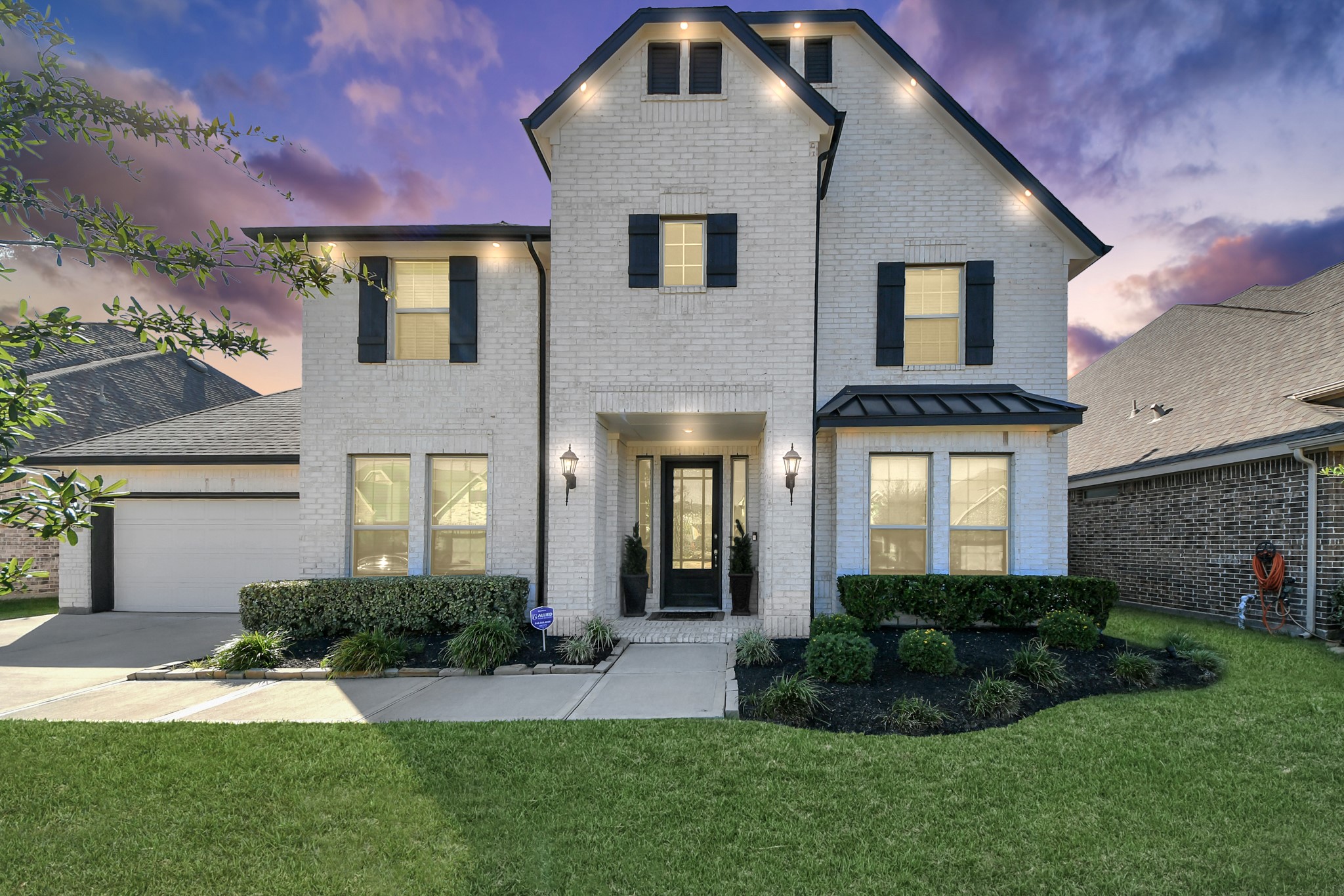 Charming two-story brick home with elegant shutters, a welcoming front porch, and beautifully manicured landscaping set against a stunning sunset sky. Charming two-story brick home with elegant shutters, a welcoming front porch, and beautifully manicured landscaping set against a stunning sunset sky.
