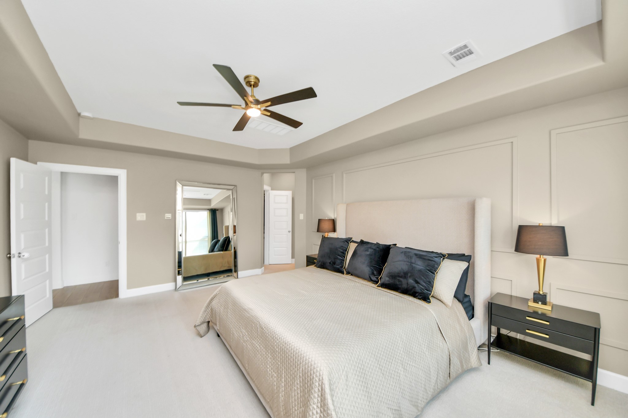 Spacious and elegant bedroom featuring a plush bed with luxurious linens, modern ceiling fan, and stylish bedside lamps, all complemented by soft neutral tones and ample natural light.