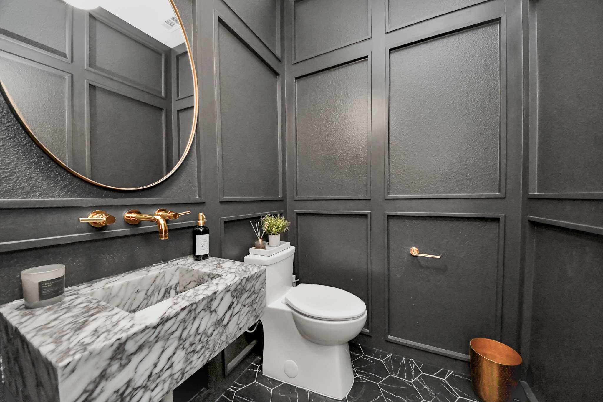 Elegant powder room featuring dark paneled walls, a striking Calacatta Viola marble floating sink, and gold accents, offering a sophisticated and modern touch.