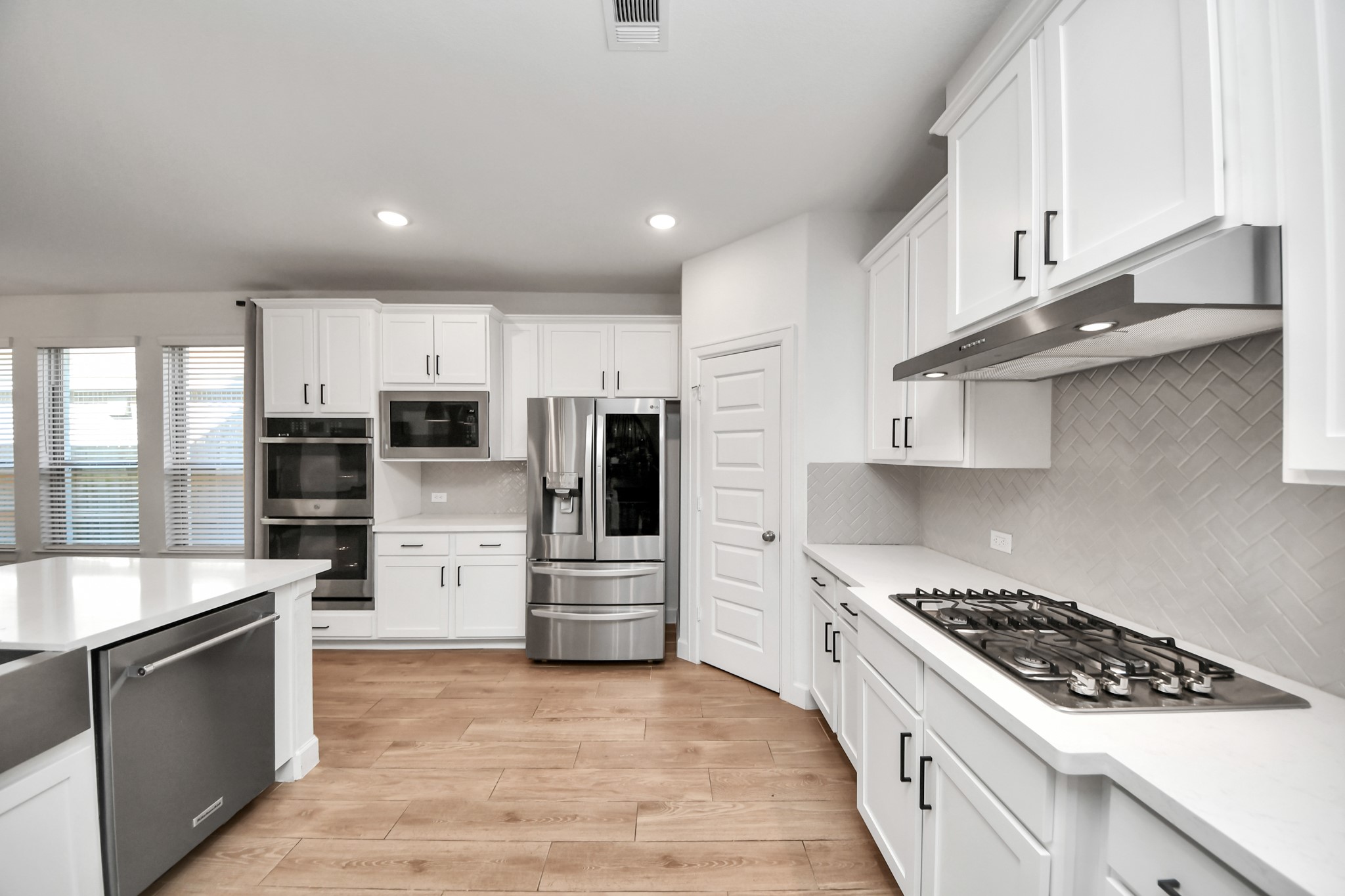 Modern kitchen with sleek stainless steel appliances, white cabinetry, and a spacious island, perfect for culinary enthusiasts.