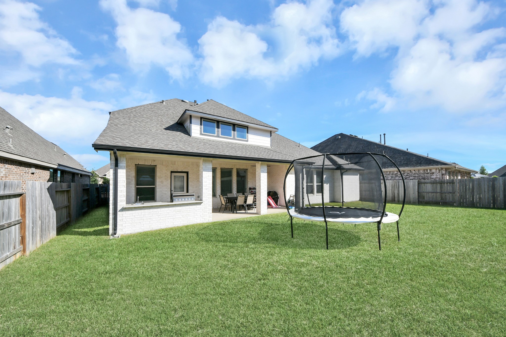 Spacious backyard with a covered patio and ample lawn space, perfect for outdoor activities and relaxation.