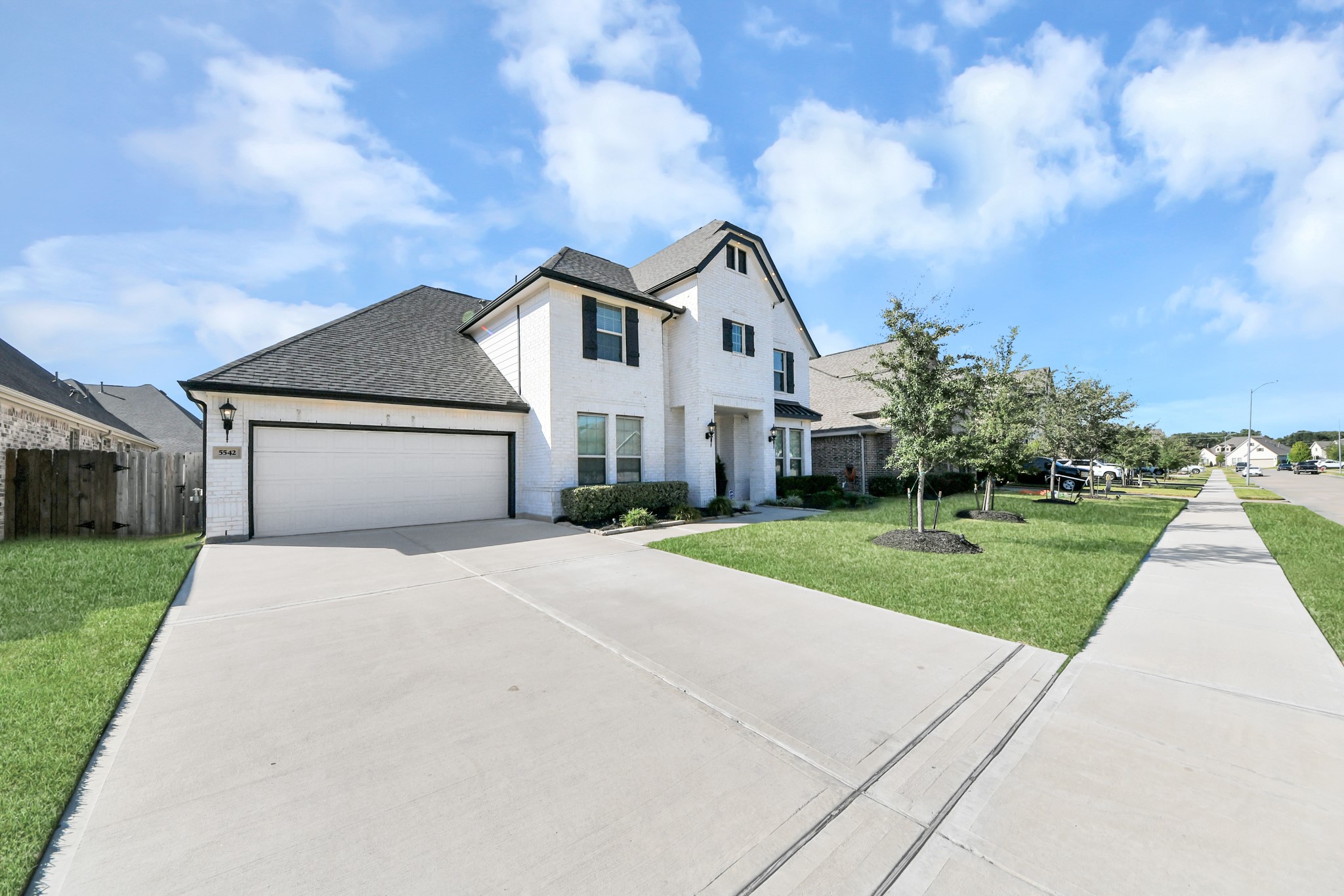 Charming two-story home with a spacious driveway, elegant brick exterior, and manicured landscaping on a peaceful suburban street.
