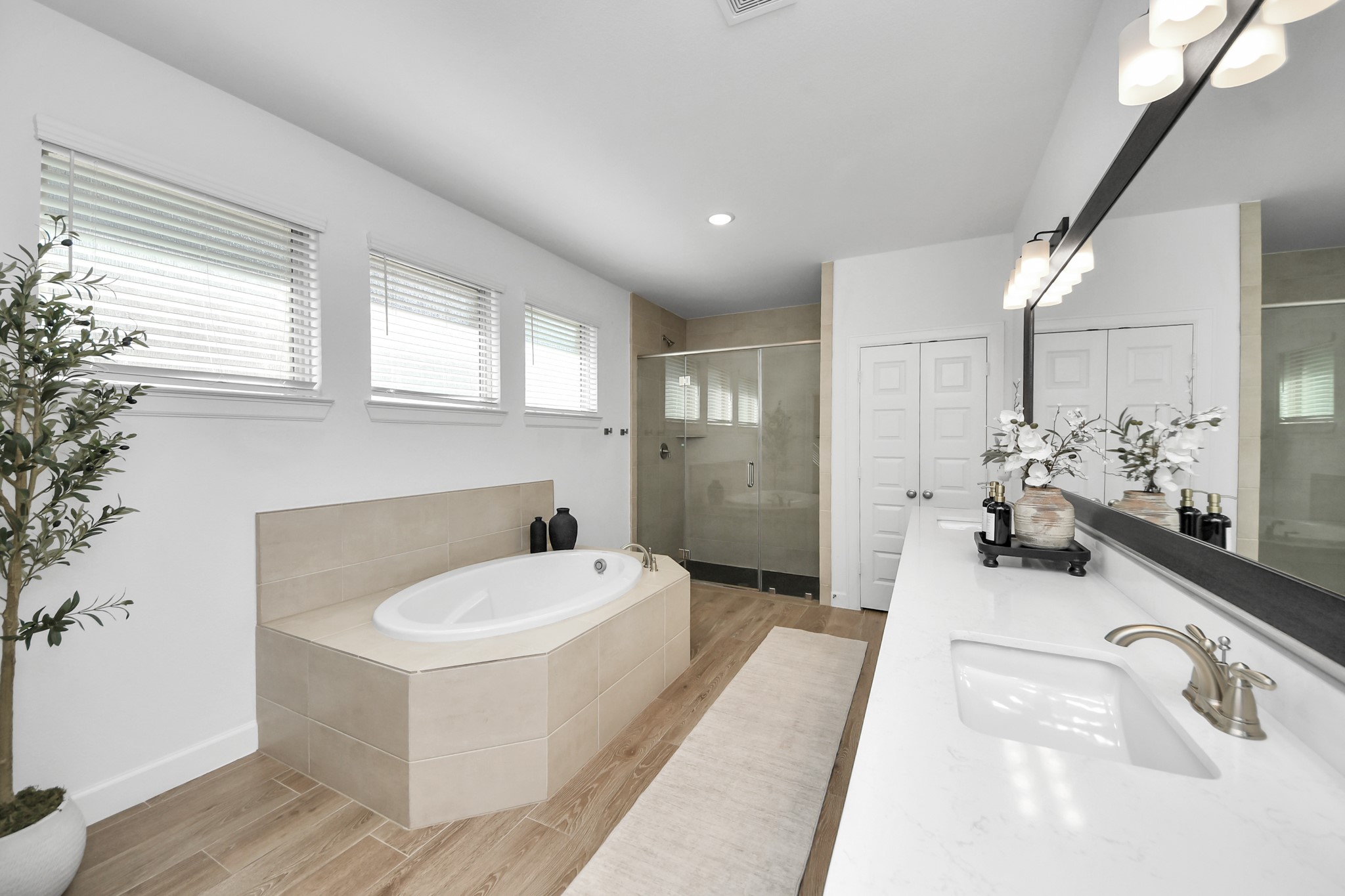 Luxurious bathroom featuring a spacious soaking tub, elegant double vanity with modern fixtures, and a sleek glass-enclosed shower, all enhanced by natural light and tasteful decor.