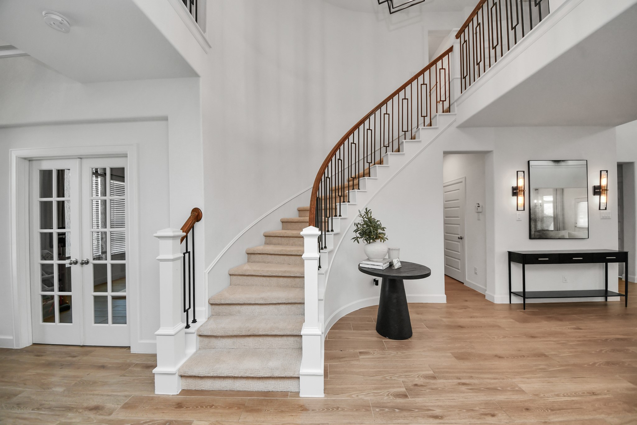 Elegant foyer with a sweeping staircase and hardwood floors, complemented by a stylish console and modern lighting.