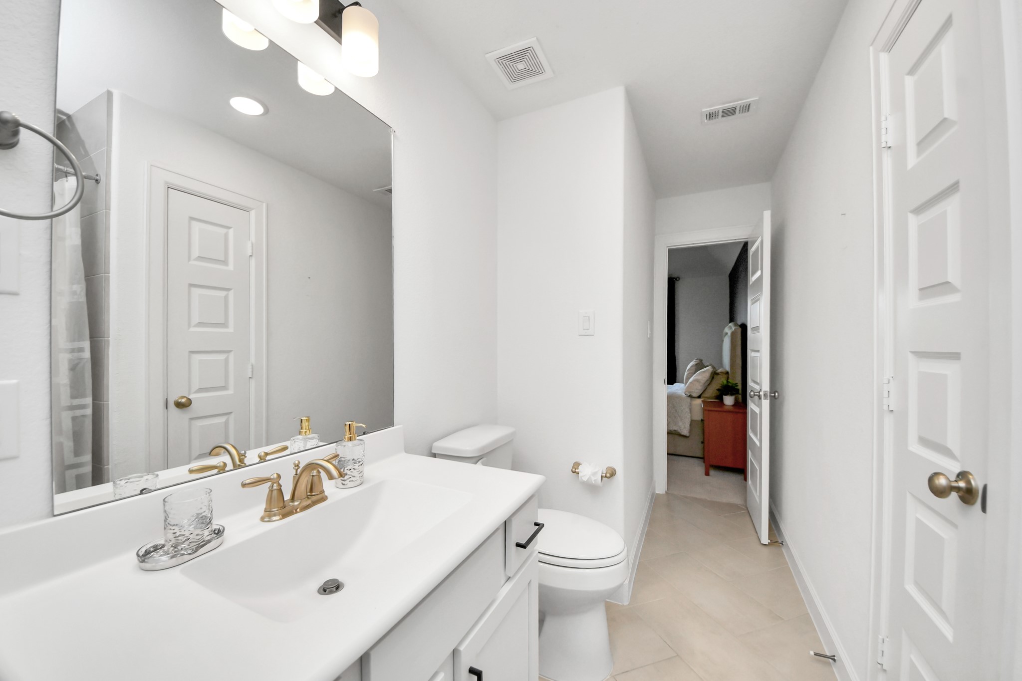 Bright and modern bathroom featuring sleek fixtures, ample lighting, and a seamless connection to the adjacent bedroom.