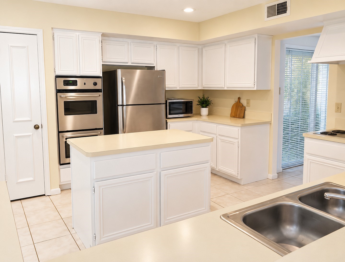 Bright kitchen with center island, ample cabinetry, and stainless steel appliances.