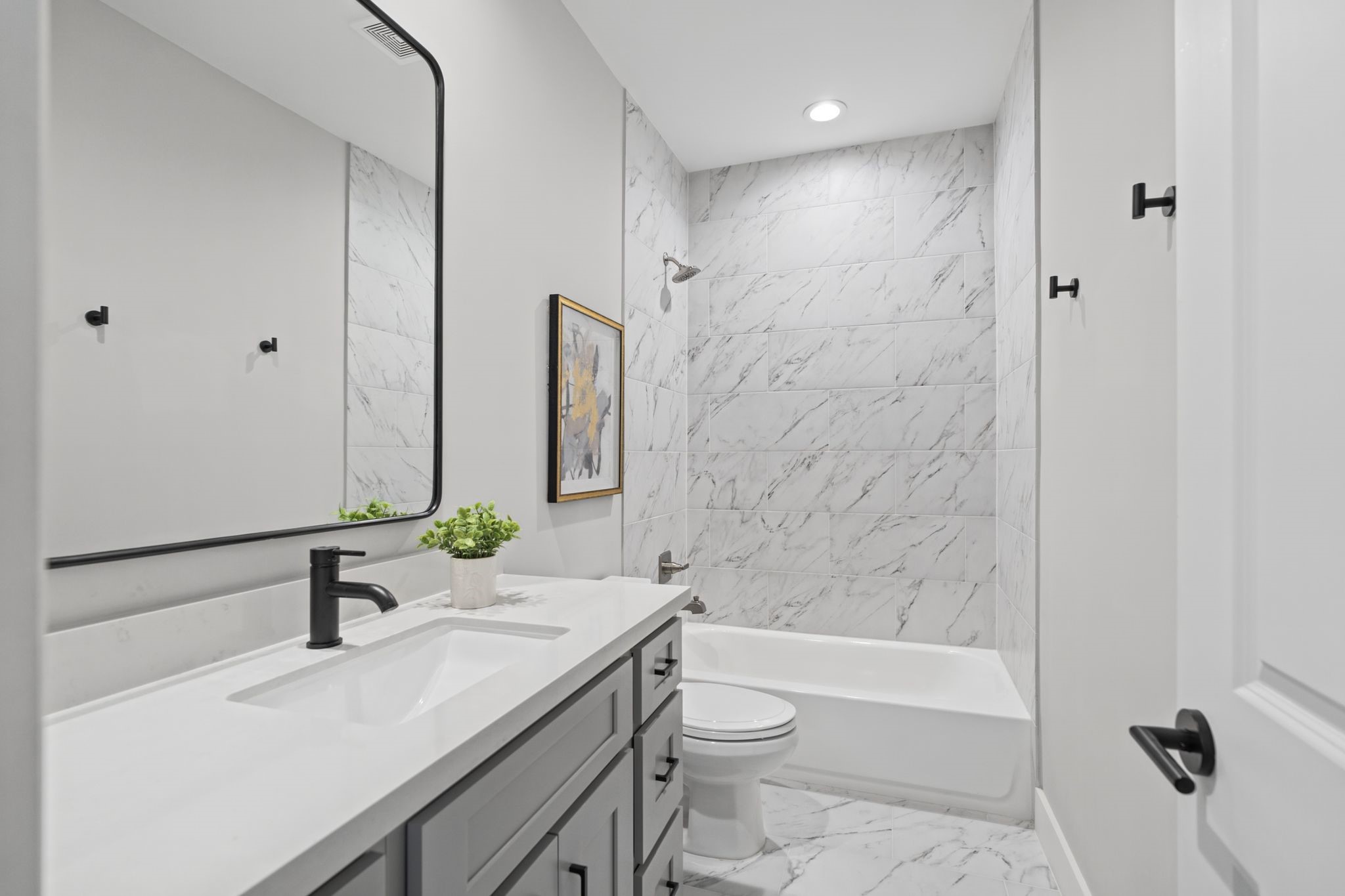 Contemporary fixtures, a streamlined vanity, and elegant marble-look tile create a fresh, timeless finish in the secondary bath.