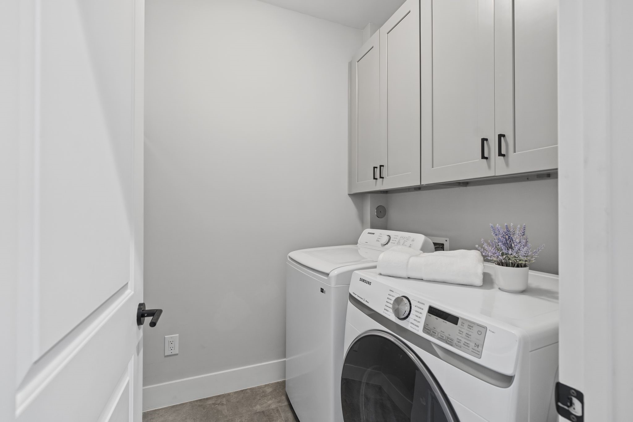 A dedicated laundry room features front-loading appliances and overhead cabinetry, keeping everyday essentials neatly organized.