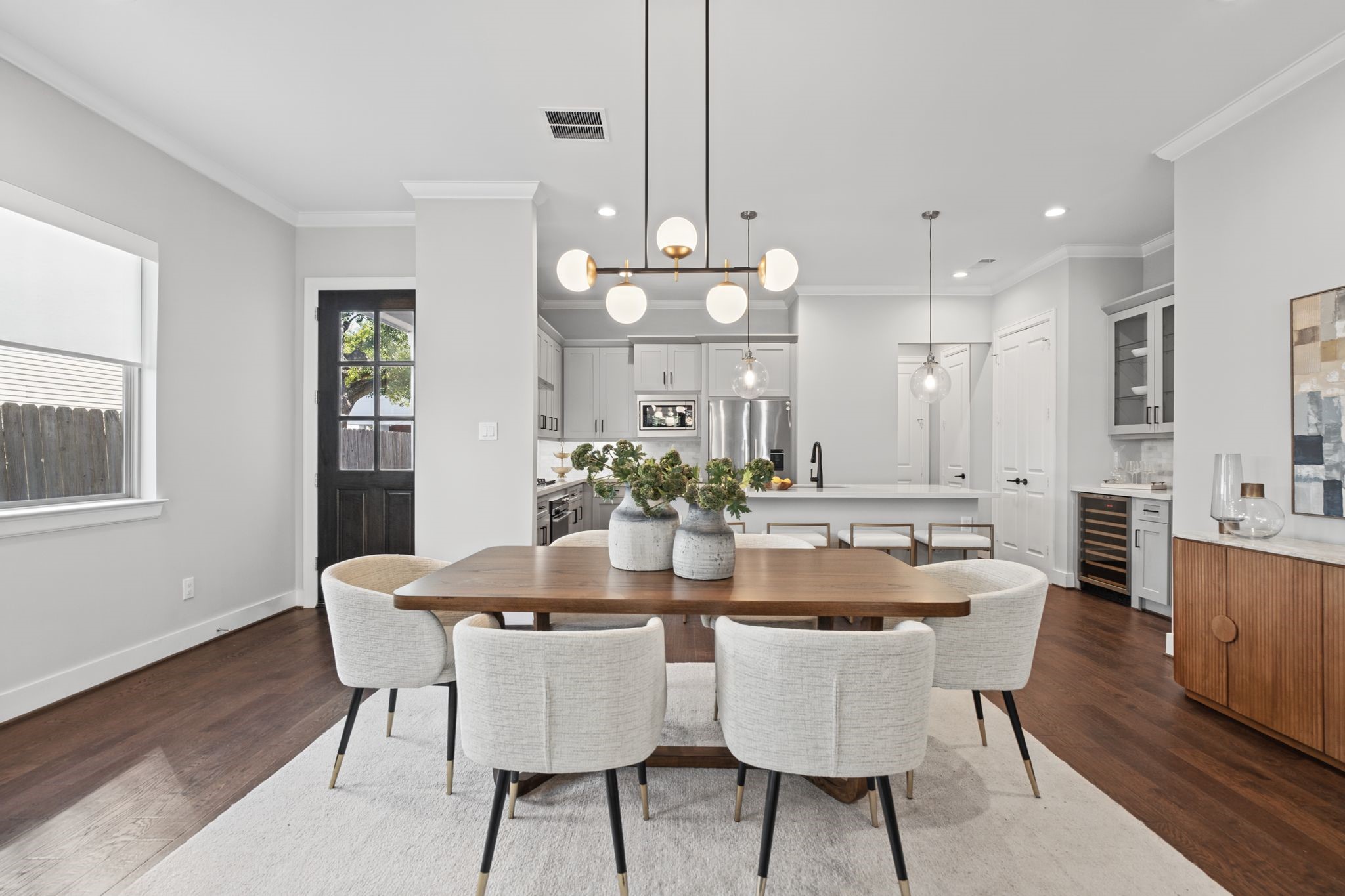 A sophisticated dining space pairs a warm wood table with upholstered seating and statement lighting, seamlessly connecting to the surrounding living areas.