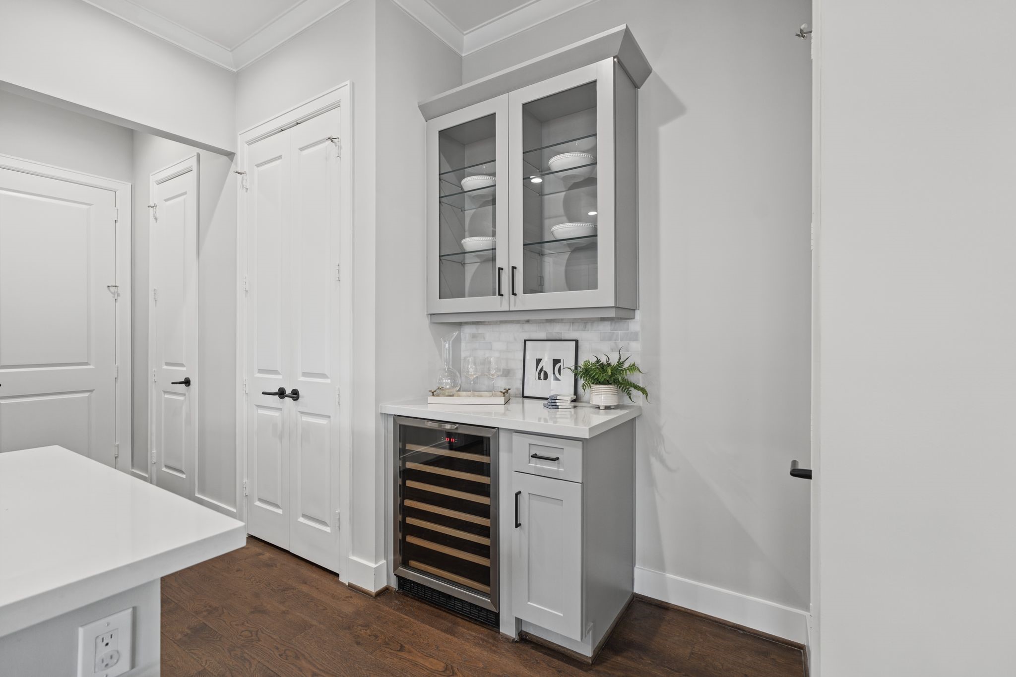 A dedicated beverage area with glass-front cabinetry and a built-in wine refrigerator adds a thoughtful touch of convenience and entertaining appeal. Notice all the additional pantry and storage closets.
