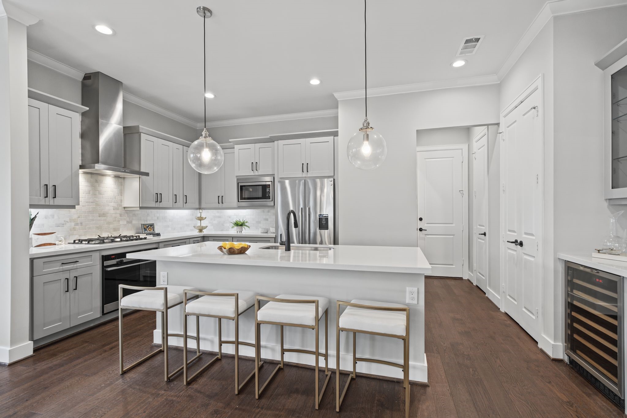 A beautifully appointed kitchen features plenty of cabinetry, quartz countertops, stainless steel appliances, and contemporary pendant lighting, blending timeless appeal with modern functionality.