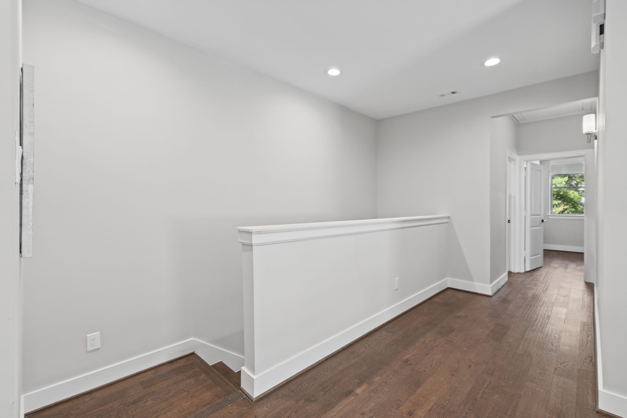 An airy landing with classic trim details and warm wood flooring continues the home's cohesive, thoughtfully finished interior design.