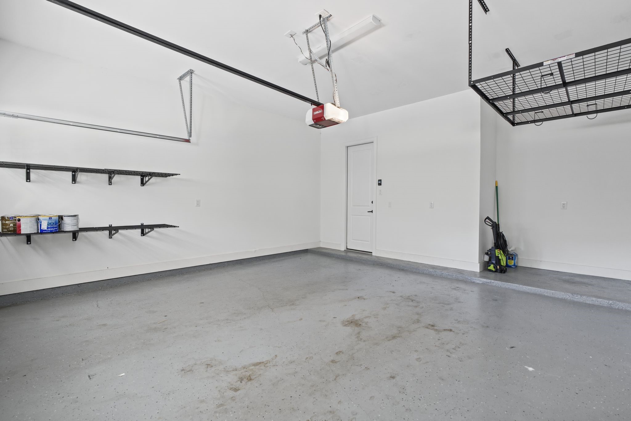 A spacious garage with organized wall-mounted storage and overhead racks provides practical space for vehicles, equipment, and seasonal essentials.