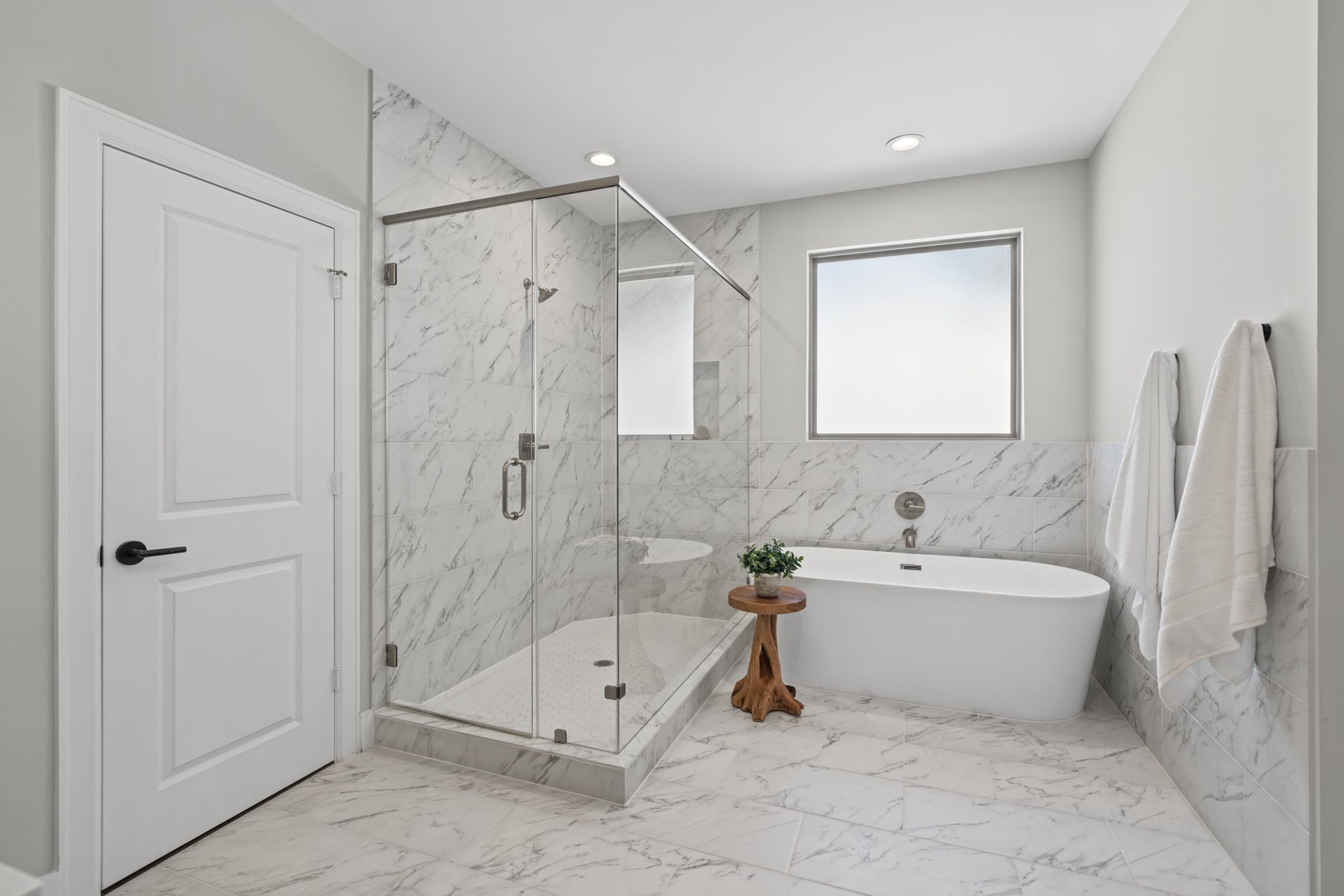 A freestanding soaking tub and glass-enclosed walk-in shower create a beautiful focal point, complemented by sophisticated tilework and clean-lined finishes.