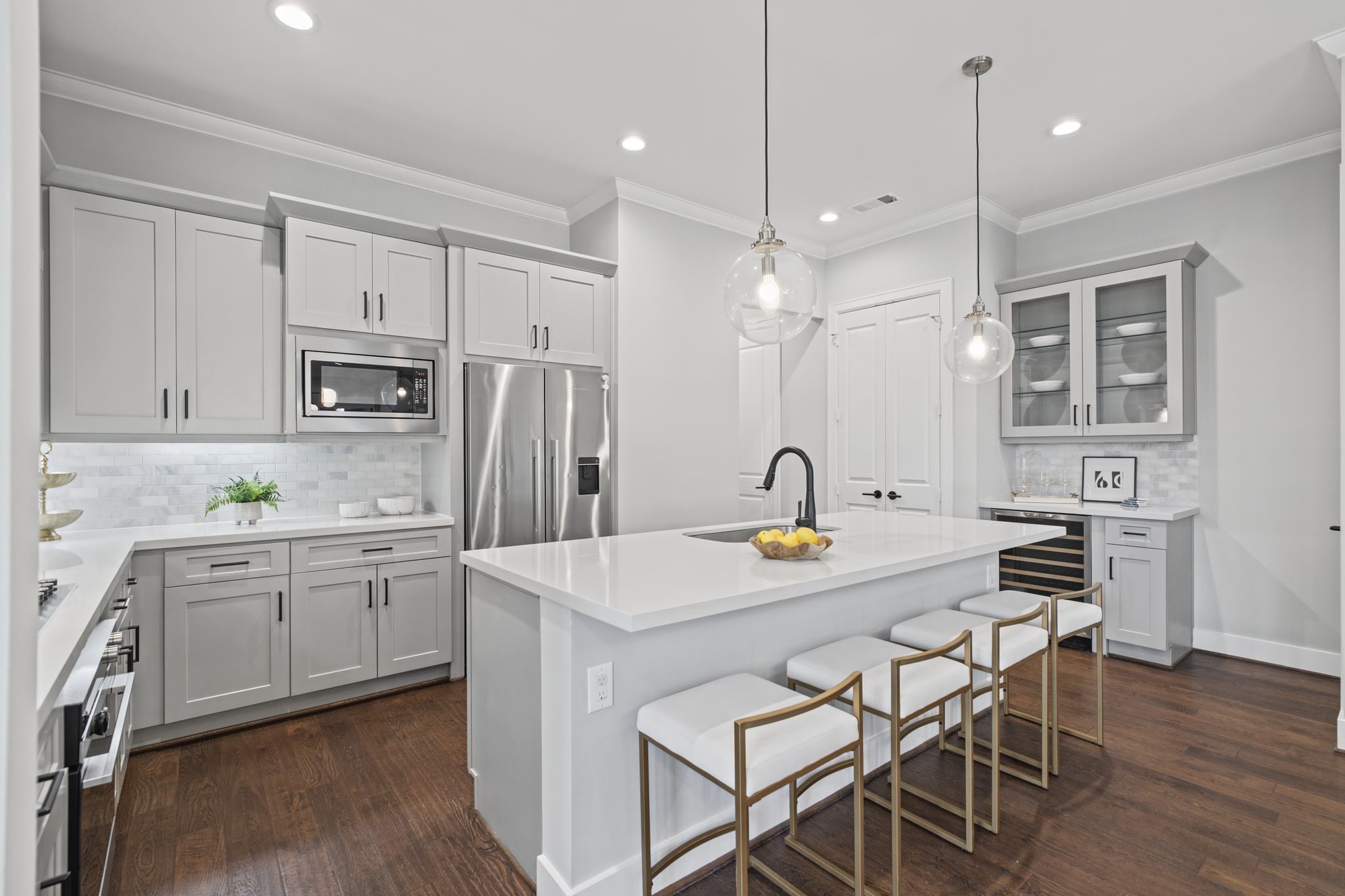 Refined cabinetry, a sophisticated backsplash, and stainless steel appliances lend the kitchen a clean, tailored aesthetic.